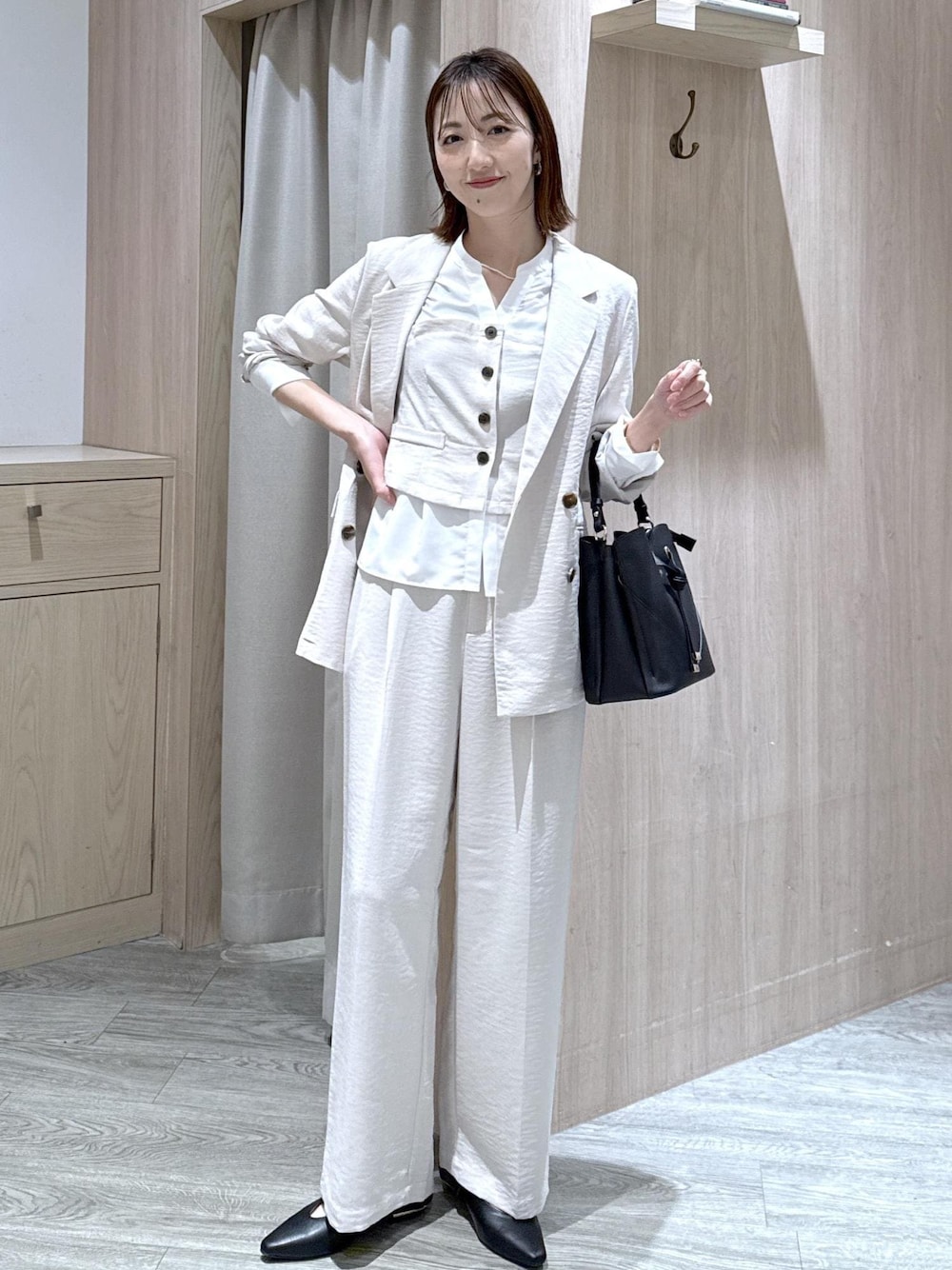 ブラック系のショルダーバッグ、ブラック系のパンプス、ホワイト系のシャツ/ブラウスを着用したレディースの春コーディネートの1枚目の写真