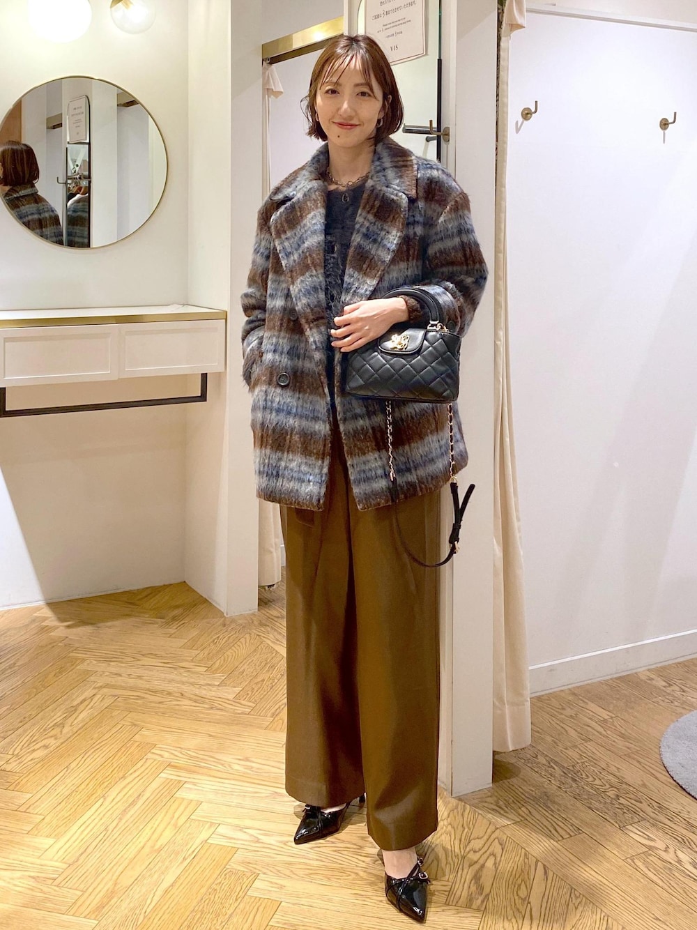 ブラック系のパンプス、グレー系のカーディガン/ボレロ、ブラウン系のピーコートを着用したレディースの冬コーディネートの1枚目の写真