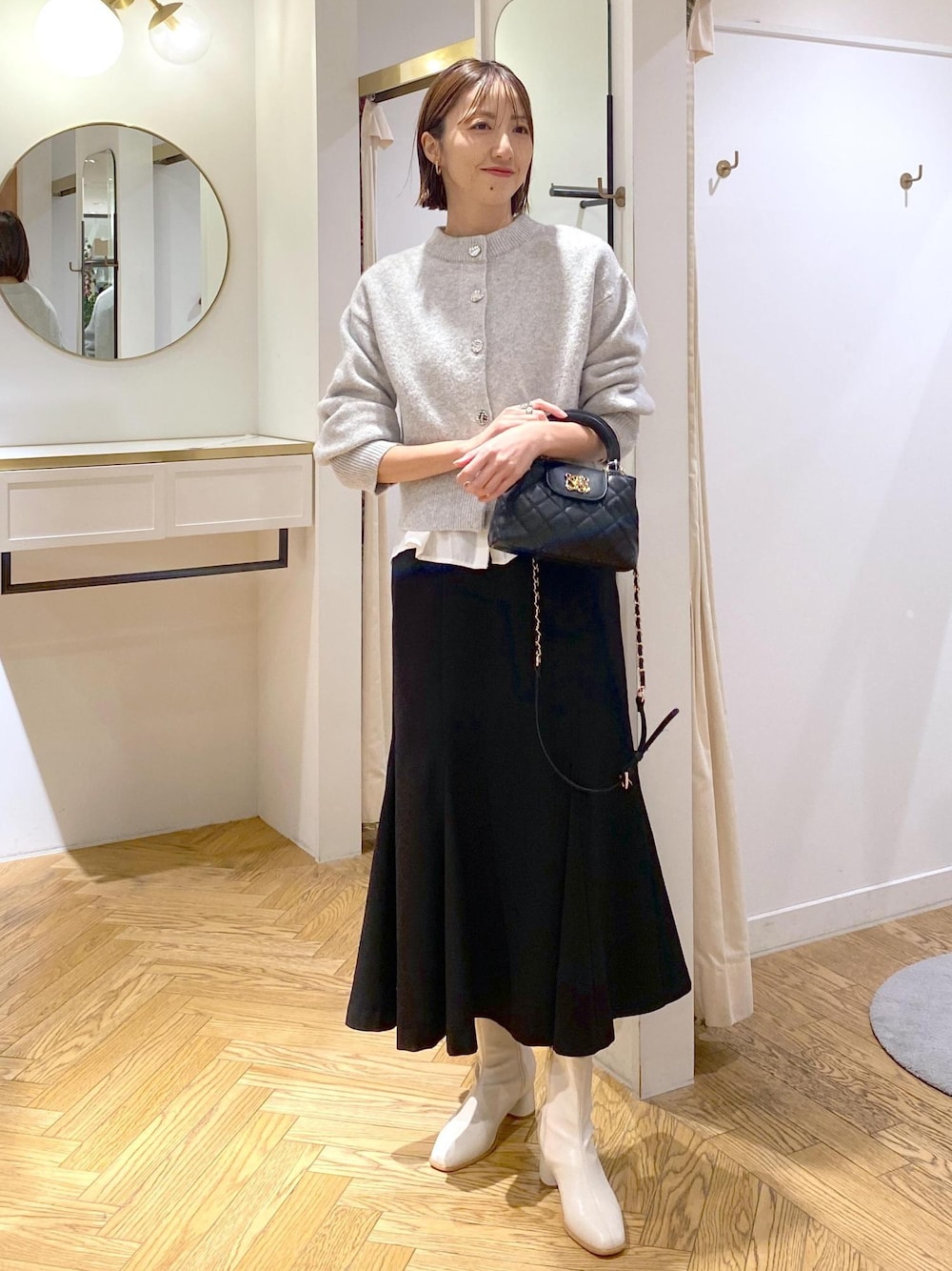 ホワイト系のシャツ/ブラウス、グレー系のカーディガン/ボレロ、ホワイト系のブーツを着用したレディースの冬コーディネートの1枚目の写真