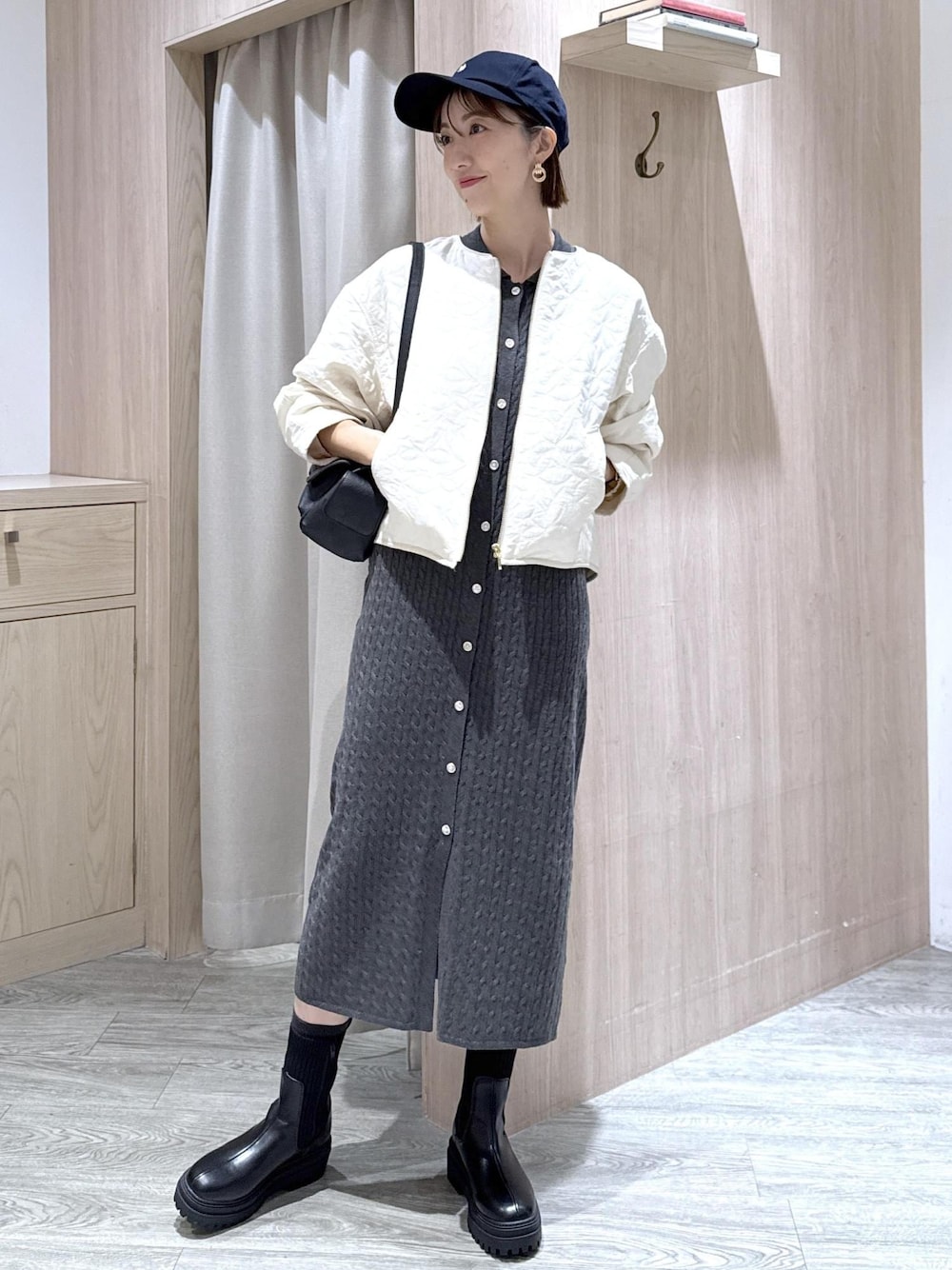 ブラック系のショルダーバッグ、ブラック系のブーツ、ホワイト系のブルゾンを着用したレディースの秋コーディネートの1枚目の写真