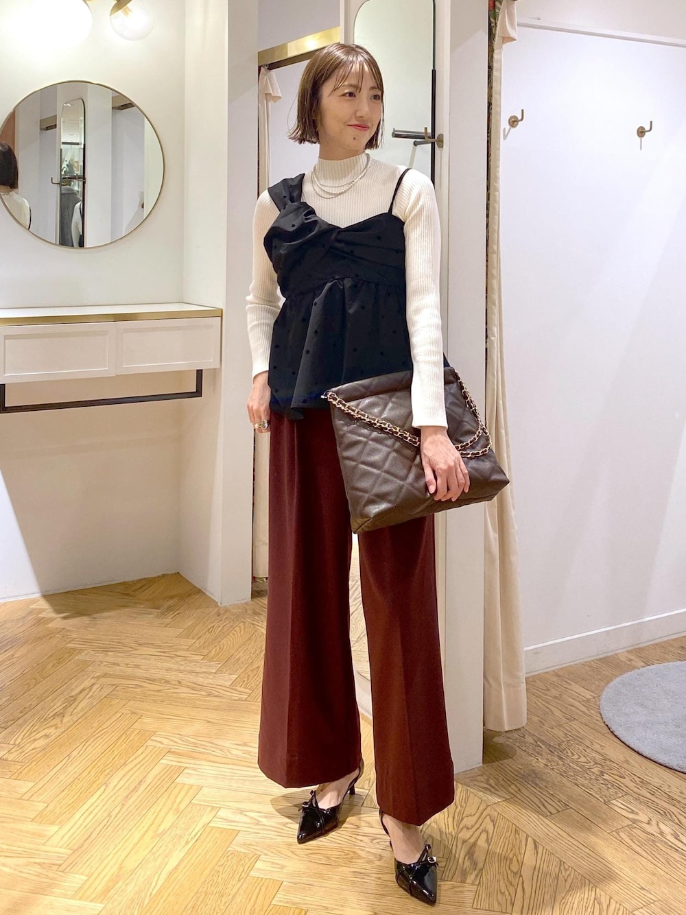 ブラック系のパンプス、ブラック系のキャミソール、ホワイト系のニット/セーターを着用したレディースの冬コーディネートの1枚目の写真