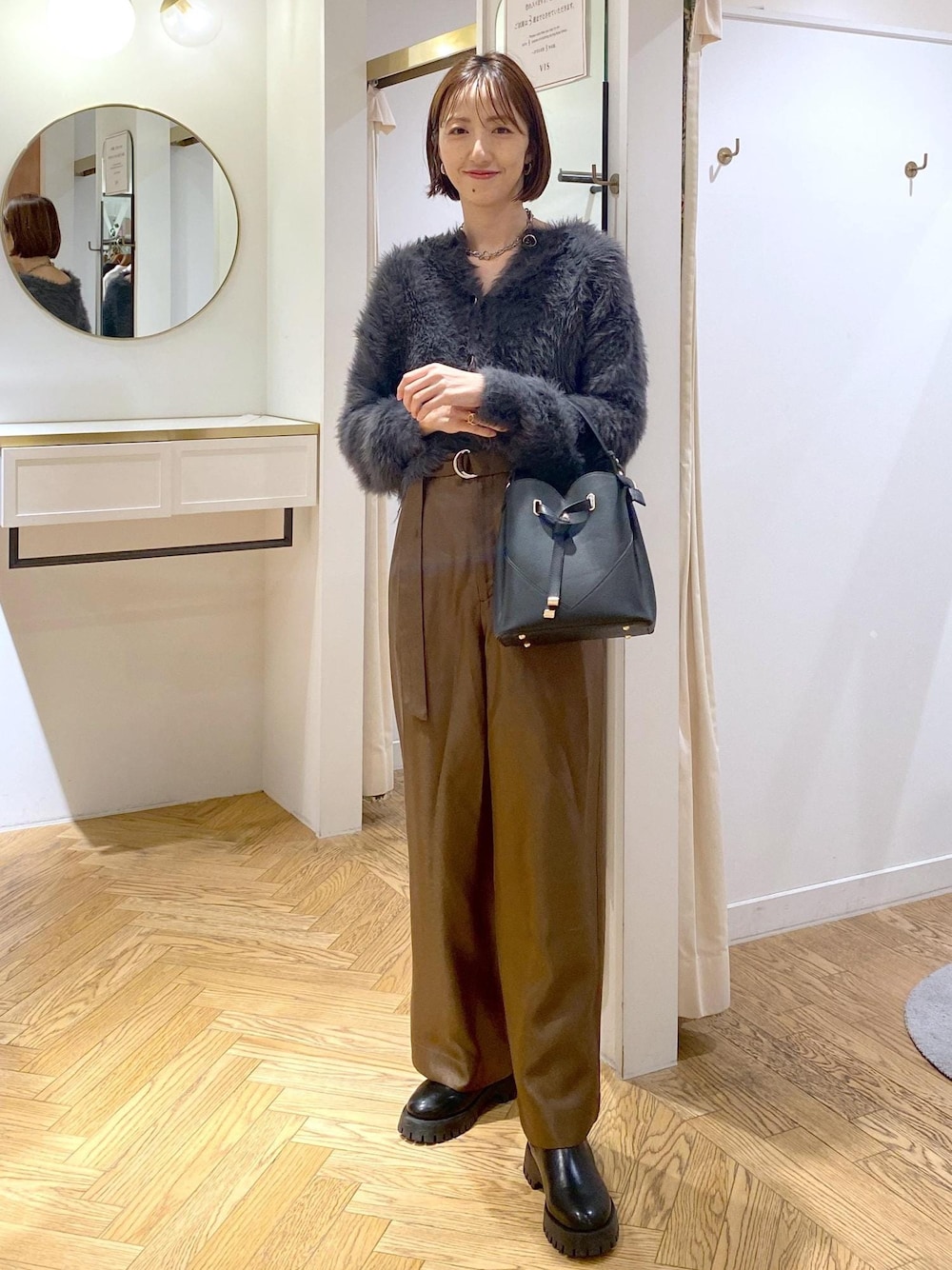 ブラック系のショルダーバッグ、ブラック系のブーツ、グレー系のカーディガン/ボレロを着用したレディースの冬コーディネートの1枚目の写真