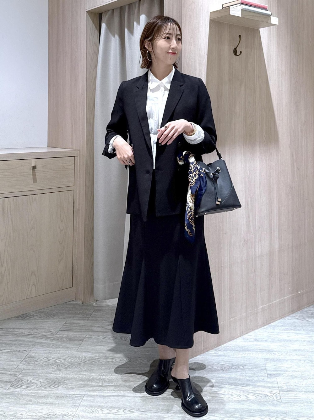ブラック系のショルダーバッグ、ブラック系のスカート、ブラック系のテーラードジャケットを着用したレディースの冬コーディネートの1枚目の写真