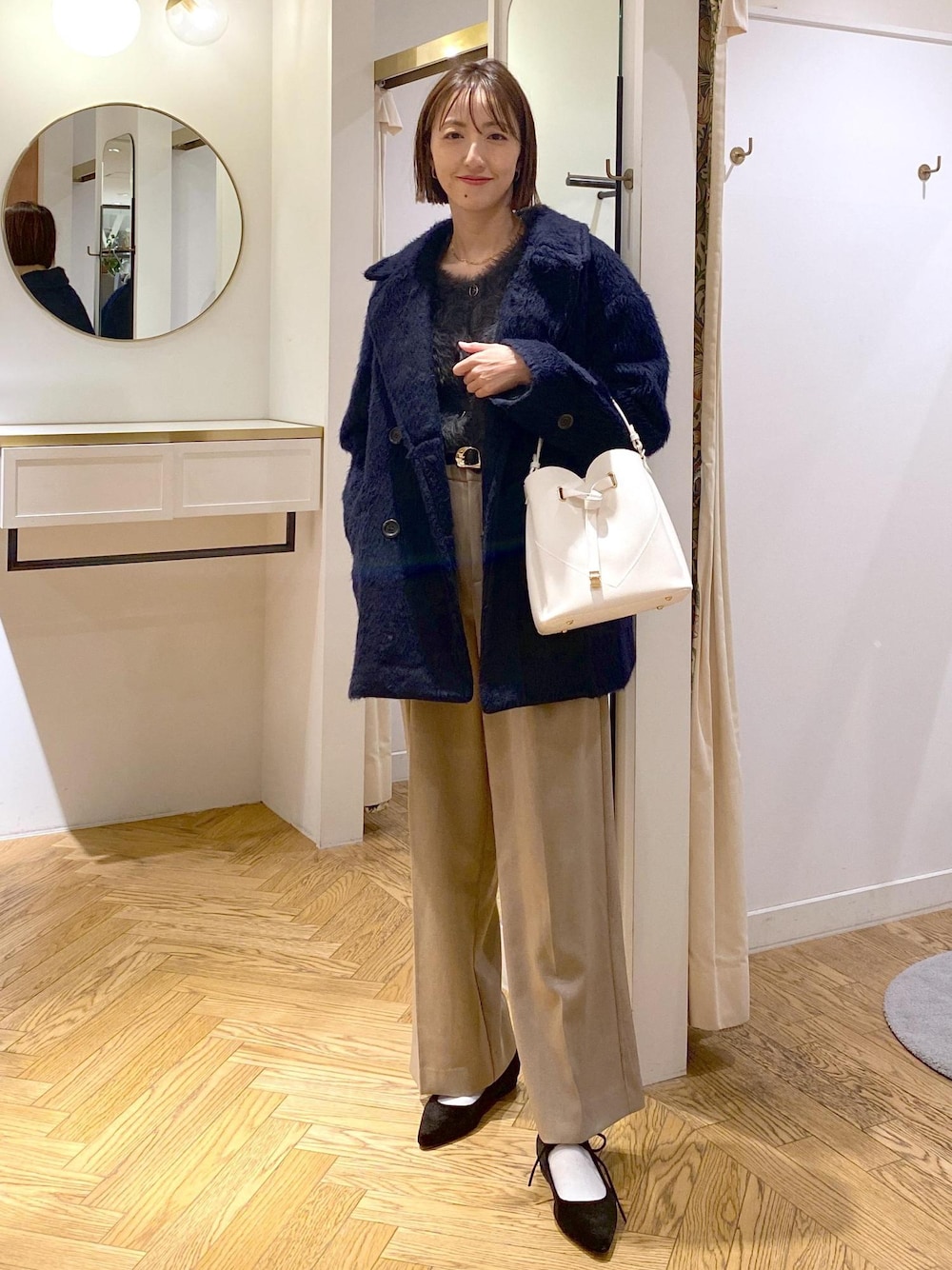 ホワイト系のショルダーバッグ、ベージュ系のスラックス、グレー系のカーディガン/ボレロを着用したレディースの冬コーディネートの1枚目の写真