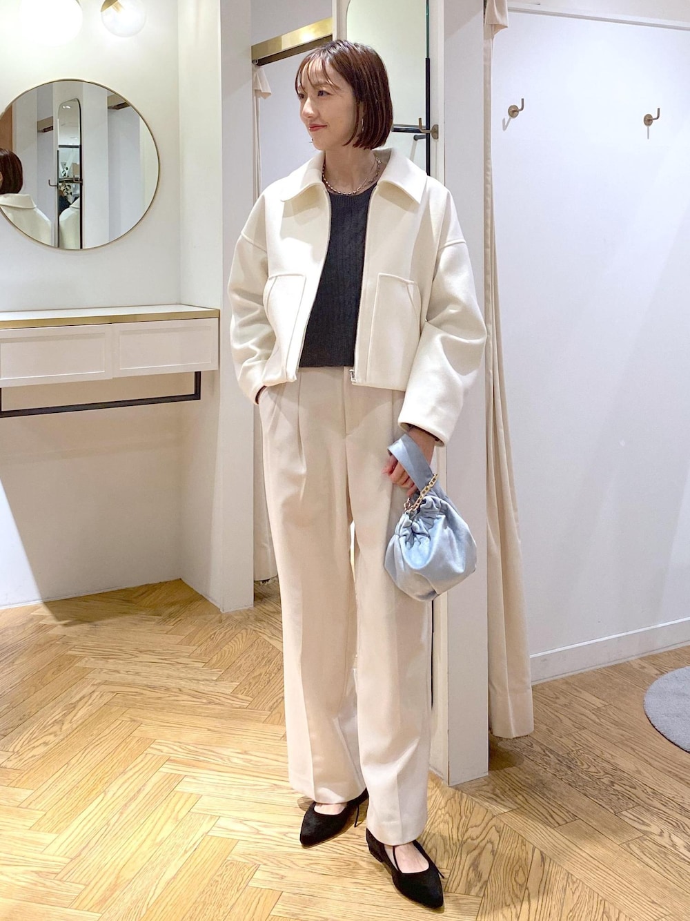 ブルー系のハンドバッグ、ホワイト系のブルゾン、ブラック系のパンプスを着用したレディースの冬コーディネートの1枚目の写真