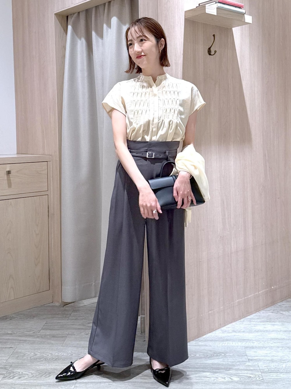 ブラック系のショルダーバッグ、ブラック系のパンプス、ホワイト系のカーディガン/ボレロを着用したレディースの夏コーディネートの1枚目の写真
