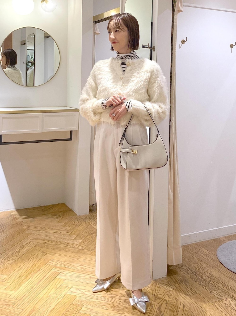 シルバー系のパンプス、ホワイト系のカーディガン/ボレロ、ホワイト系のTシャツ/カットソーを着用したレディースの冬コーディネートの1枚目の写真