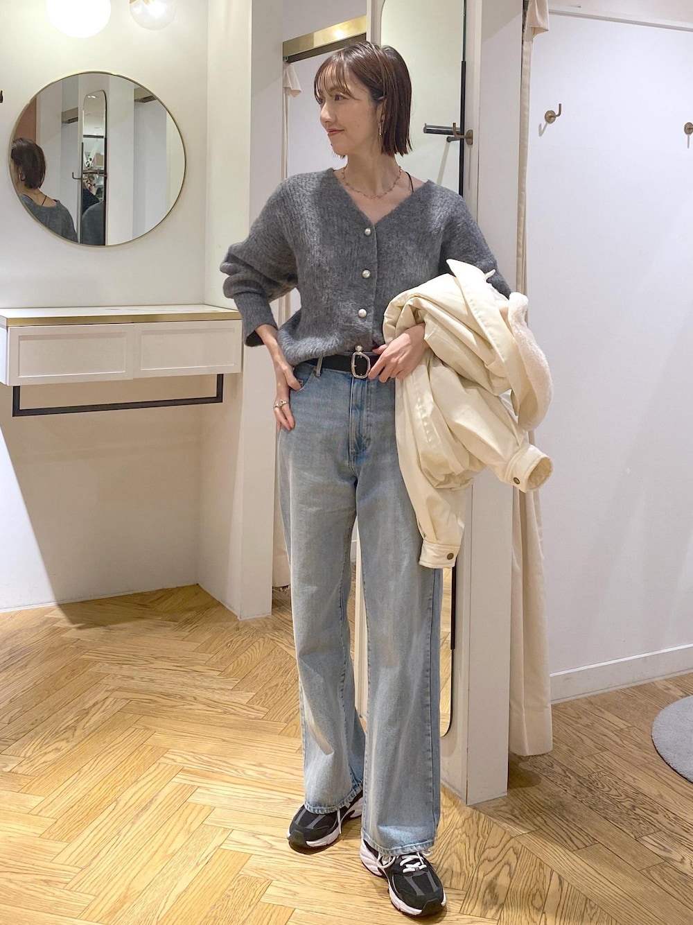 シルバー系のショルダーバッグ、ブルー系のデニムパンツ、グレー系のカーディガン/ボレロを着用したレディースの冬コーディネートの1枚目の写真