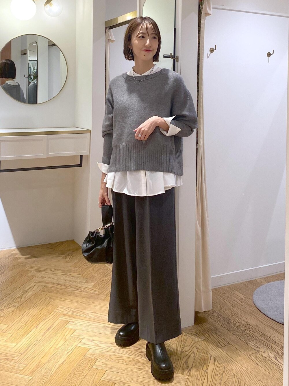 ブラック系のブーツ、ホワイト系のシャツ/ブラウス、グレー系のニット/セーターを着用したレディースの冬コーディネートの1枚目の写真