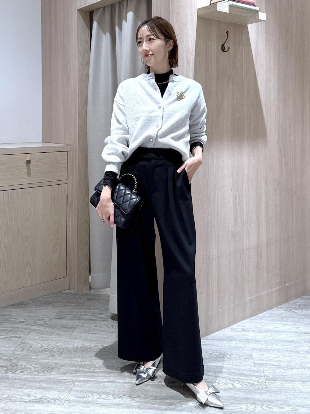 シルバー系のパンプス、グレー系のカーディガン/ボレロ、ブラック系のTシャツ/カットソーを着用したレディースの冬コーディネートの1枚目の写真
