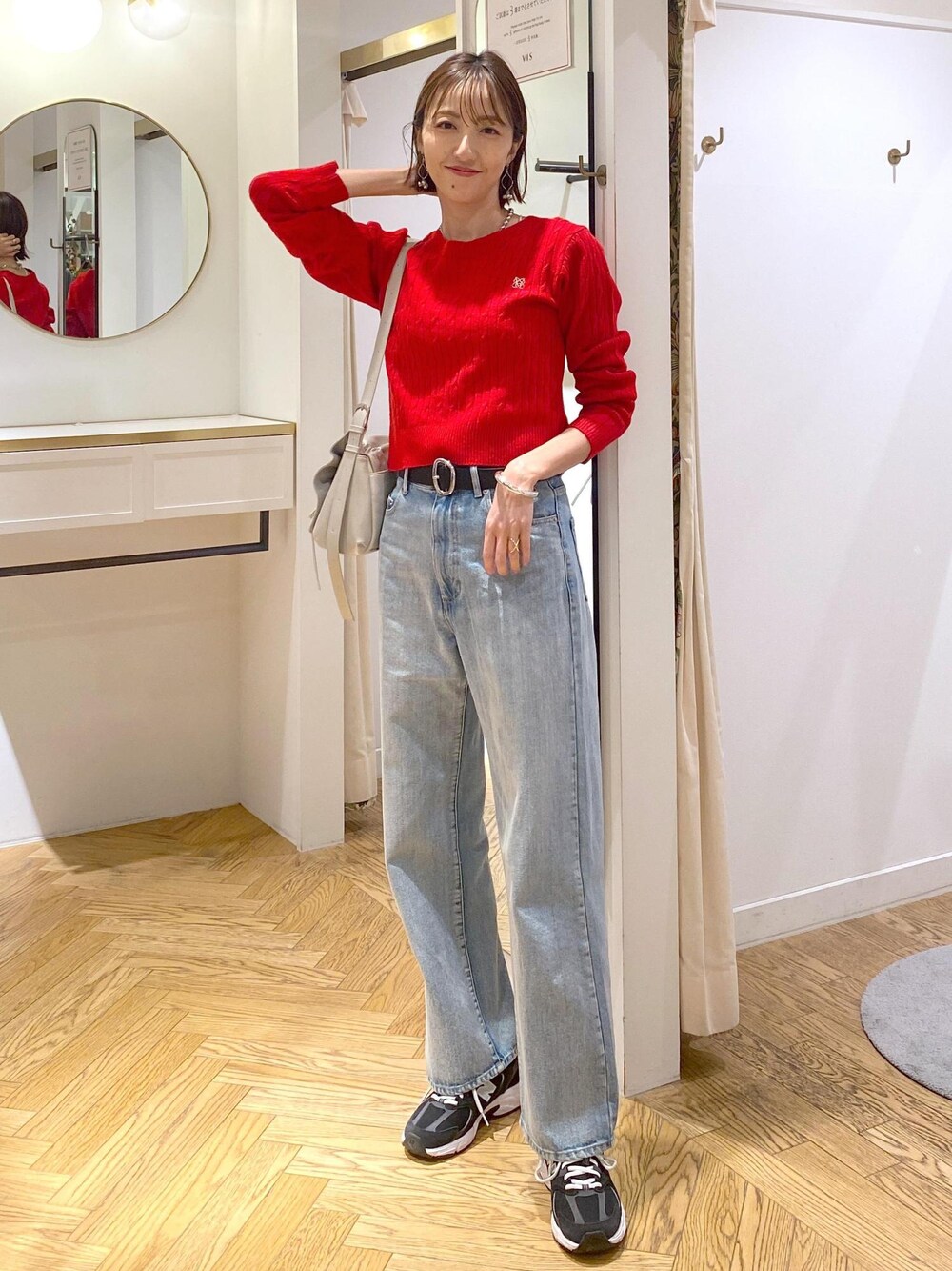 レッド系のニット/セーター、ブルー系のデニムパンツ、ブラック系のベルトを着用したレディースの冬コーディネートの1枚目の写真