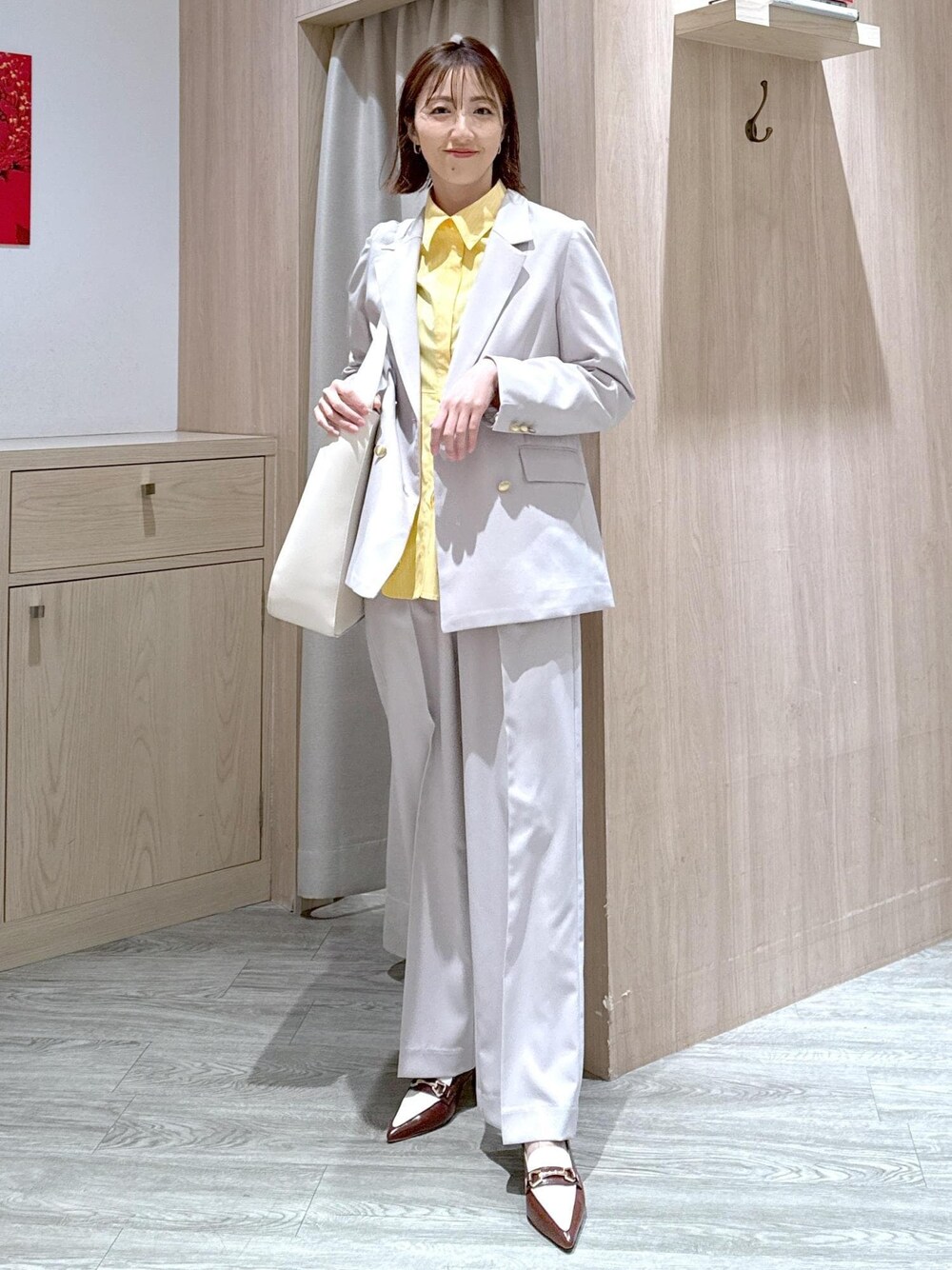 ブラウン系のパンプス、イエロー系のシャツ/ブラウス、ベージュ系のスラックスを着用したレディースの春コーディネートの1枚目の写真