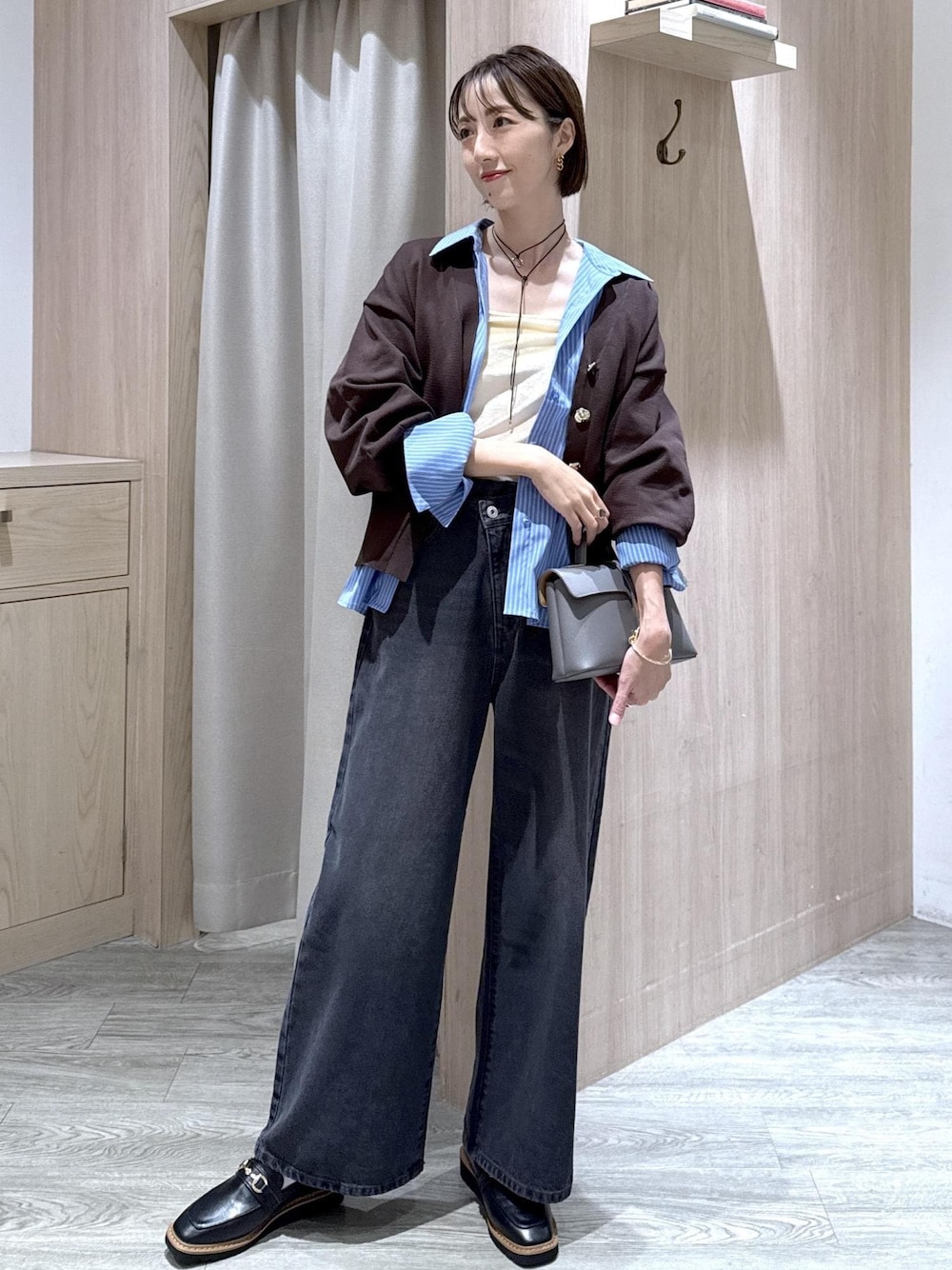 グレー系のショルダーバッグ、ブラック系のローファー、ホワイト系のキャミソールを着用したレディースの秋コーディネートの1枚目の写真