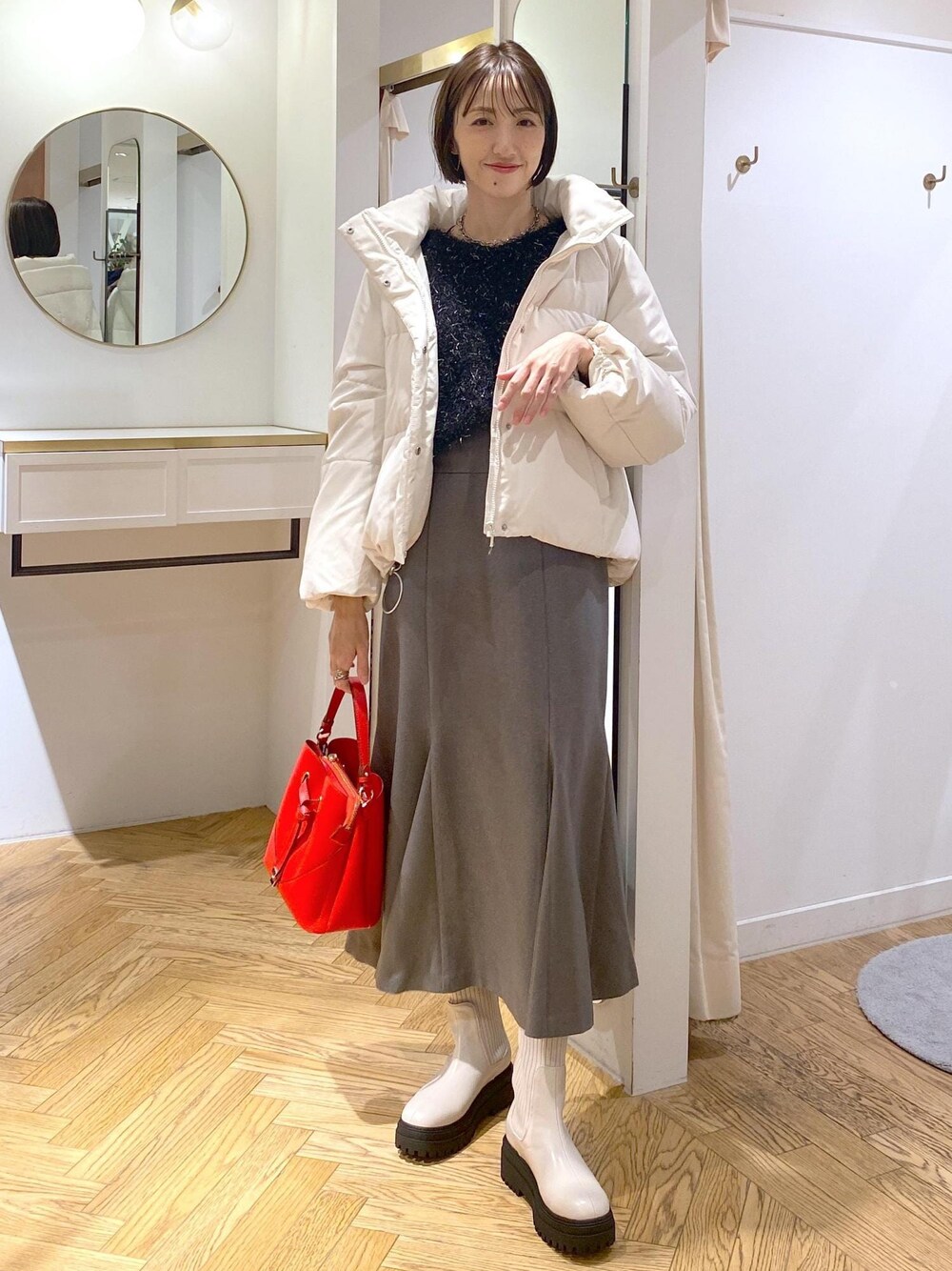 ホワイト系のブーツ、グレー系のスカート、ホワイト系のダウンジャケット/コートを着用したレディースの冬コーディネートの1枚目の写真