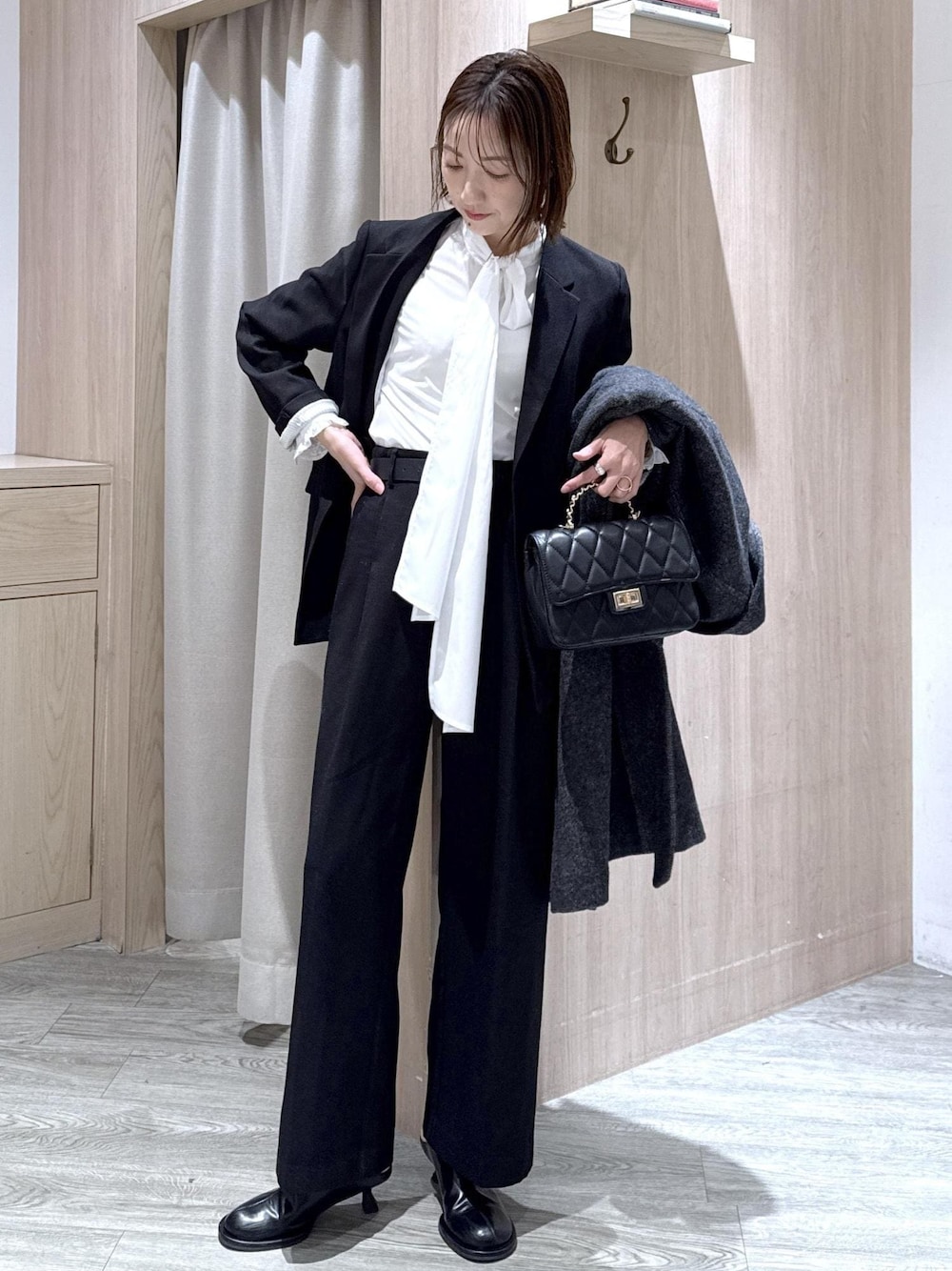 ブラック系のスラックス、ブラック系のテーラードジャケット、グレー系のその他アウターを着用したレディースの冬コーディネートの1枚目の写真