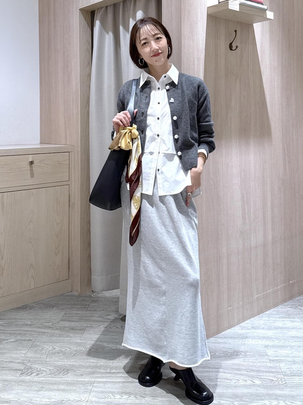 ブラック系のトートバッグ、グレー系のスカート、ホワイト系のシャツ/ブラウスを着用したレディースの秋コーディネートの1枚目の写真