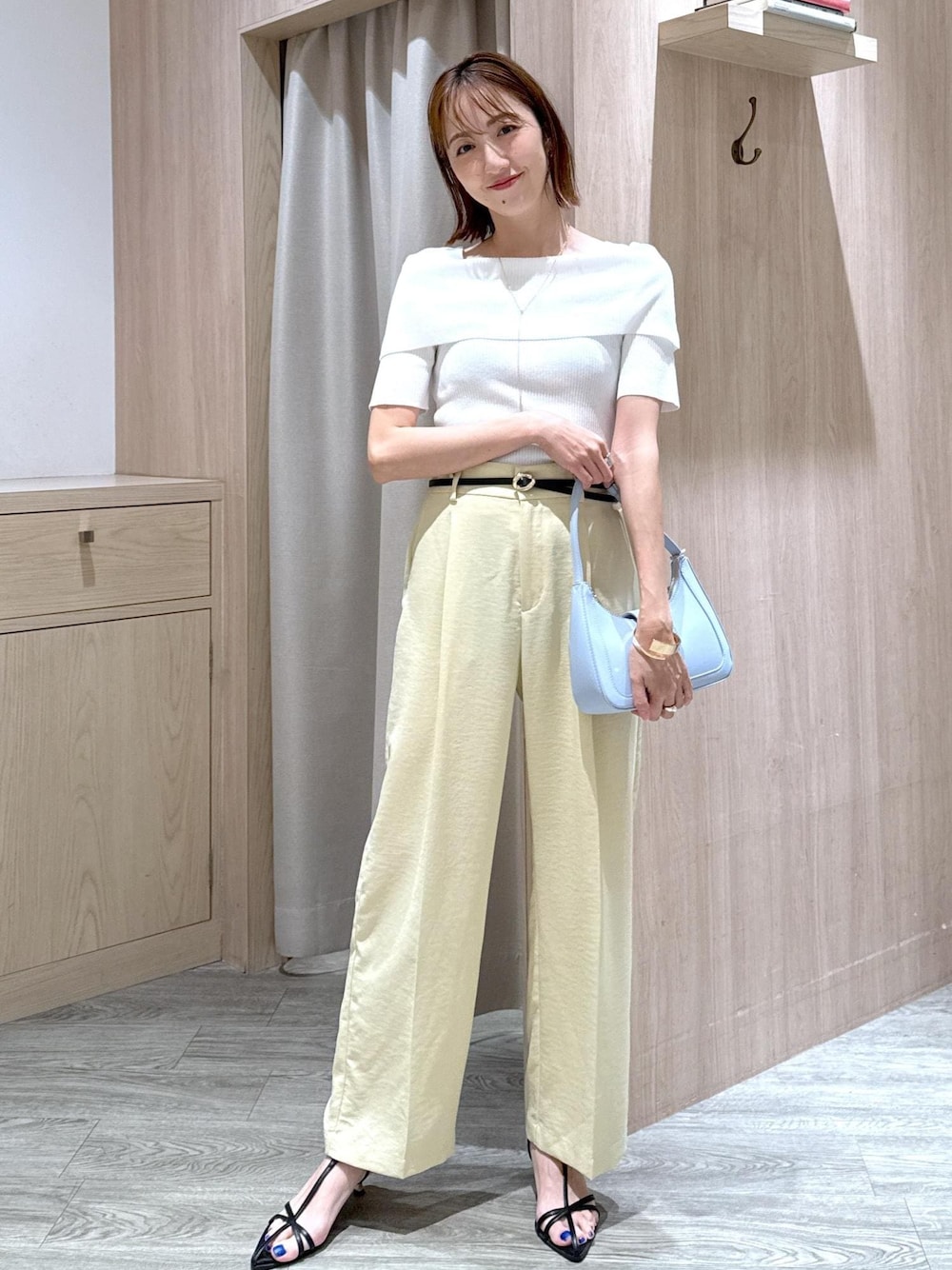 ブルー系のハンドバッグ、ブラック系のサンダル、イエロー系のスラックスを着用したレディースの夏コーディネートの1枚目の写真