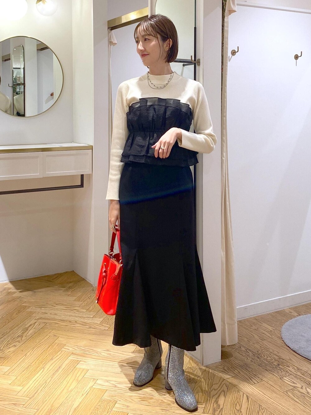 シルバー系のブーツ、ブラック系のスカート、ホワイト系のニット/セーターを着用したレディースの冬コーディネートの1枚目の写真