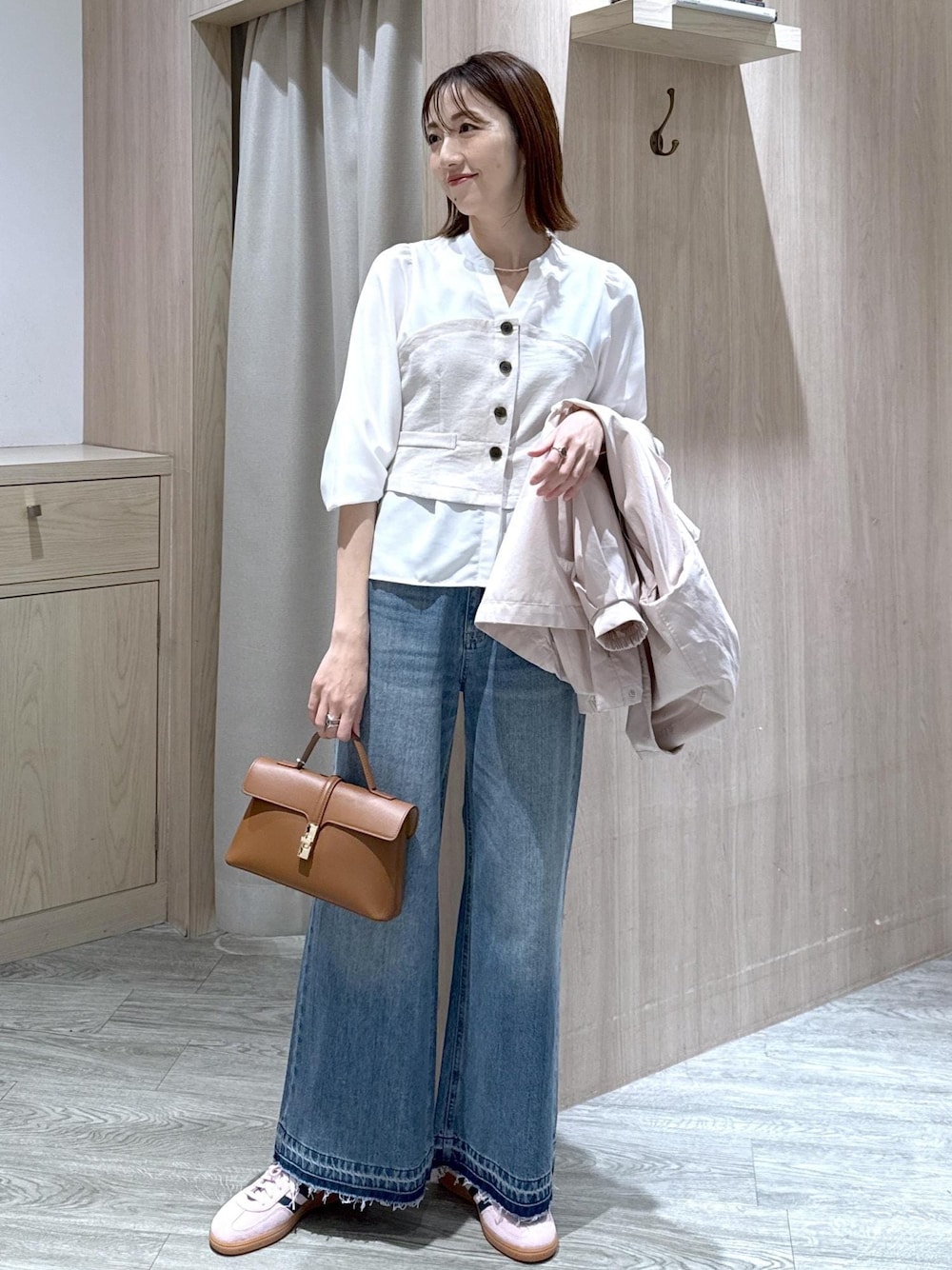 イエロー系のショルダーバッグ、ピンク系のナイロンジャケット、ブルー系のデニムパンツを着用したレディースの春コーディネートの1枚目の写真