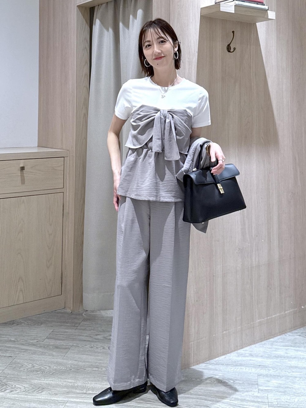 ブラック系のハンドバッグ、ブラック系のパンプス、グレー系のTシャツ/カットソーを着用したレディースの春コーディネートの1枚目の写真