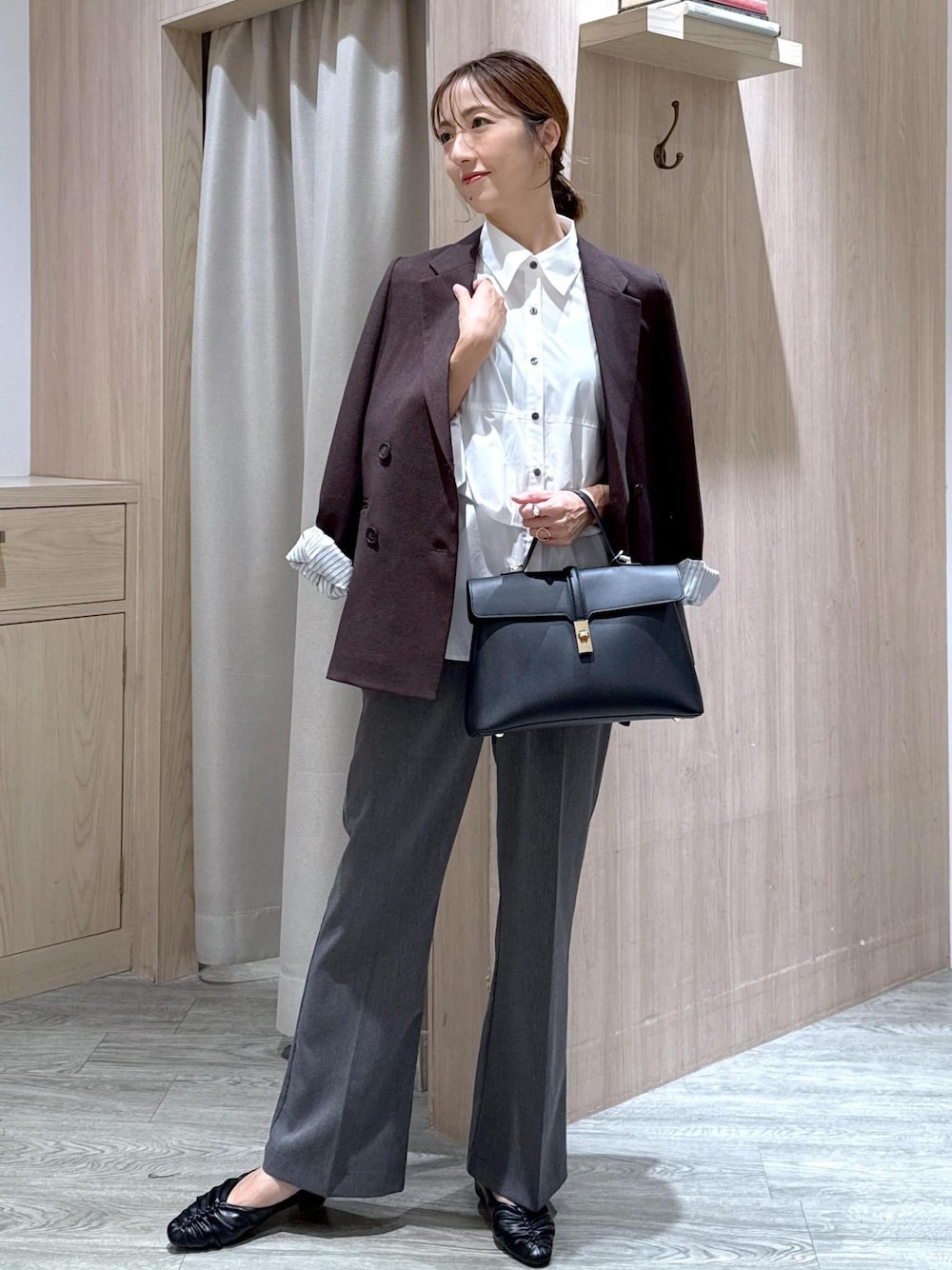 ブラック系のハンドバッグ、ブラック系のパンプス、ホワイト系のシャツ/ブラウスを着用したレディースの秋コーディネートの1枚目の写真