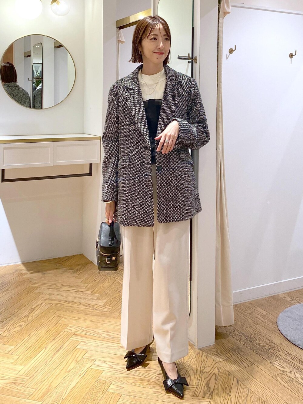 ブラック系のパンプス、ホワイト系のニット/セーター、ホワイト系のスラックスを着用したレディースの冬コーディネートの1枚目の写真