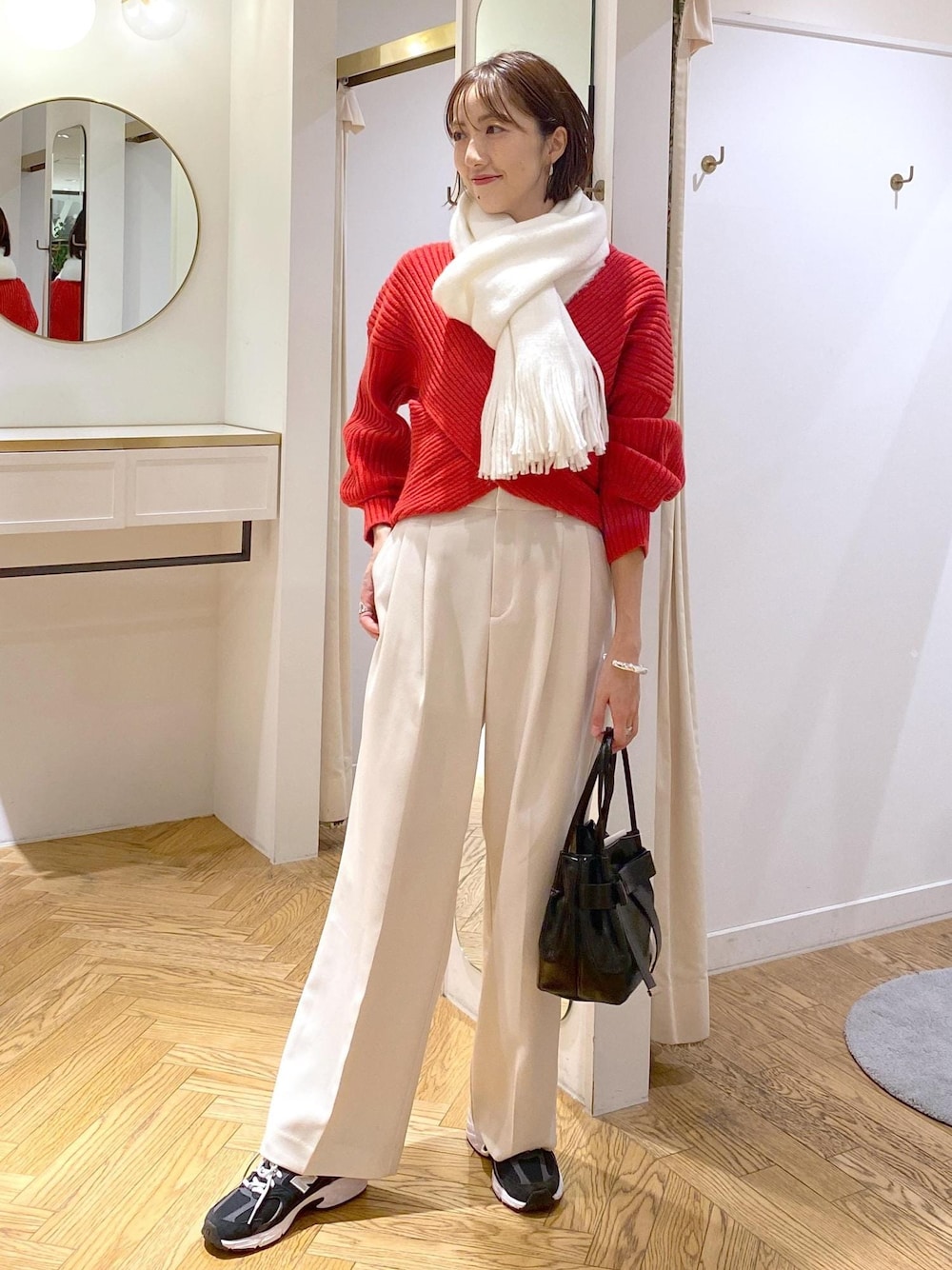 レッド系のニット/セーター、ホワイト系のスラックス、ブラック系のショルダーバッグを着用したレディースの冬コーディネートの1枚目の写真