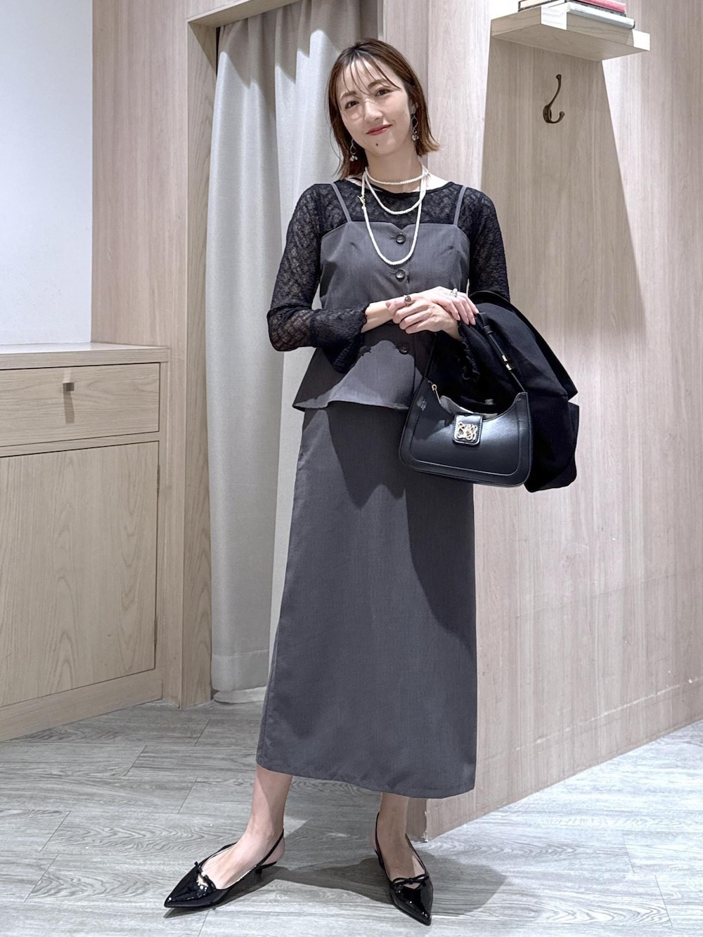 ブラック系のハンドバッグ、ブラック系のキャミソール、ブラック系のパンプスを着用したレディースの秋コーディネートの1枚目の写真