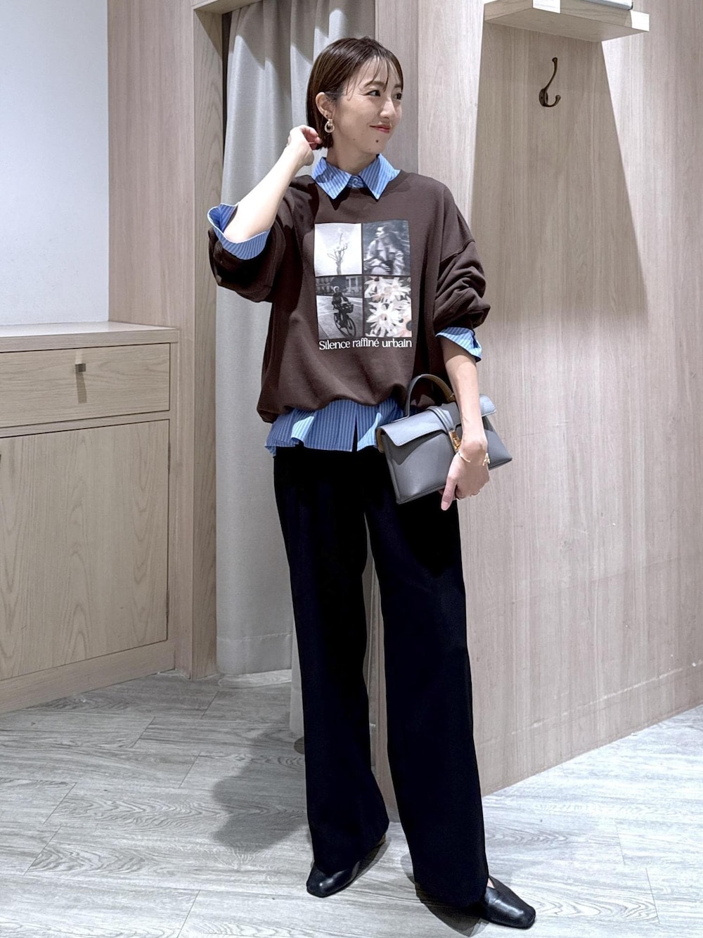 グレー系のショルダーバッグ、ブラック系のスラックス、ブルー系のシャツ/ブラウスを着用したレディースの秋コーディネートの1枚目の写真