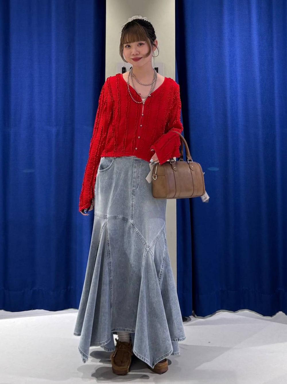 ホワイト系のキャミソール、ブラウン系のボストンバッグ、ブルー系のデニムスカートを着用したレディースの春コーディネートの1枚目の写真