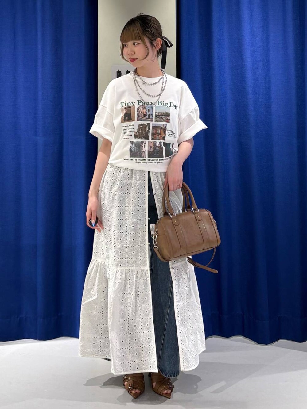 ブルー系のデニムパンツ、ブラウン系のボストンバッグ、ホワイト系のTシャツ/カットソーを着用したレディースの春コーディネートの1枚目の写真
