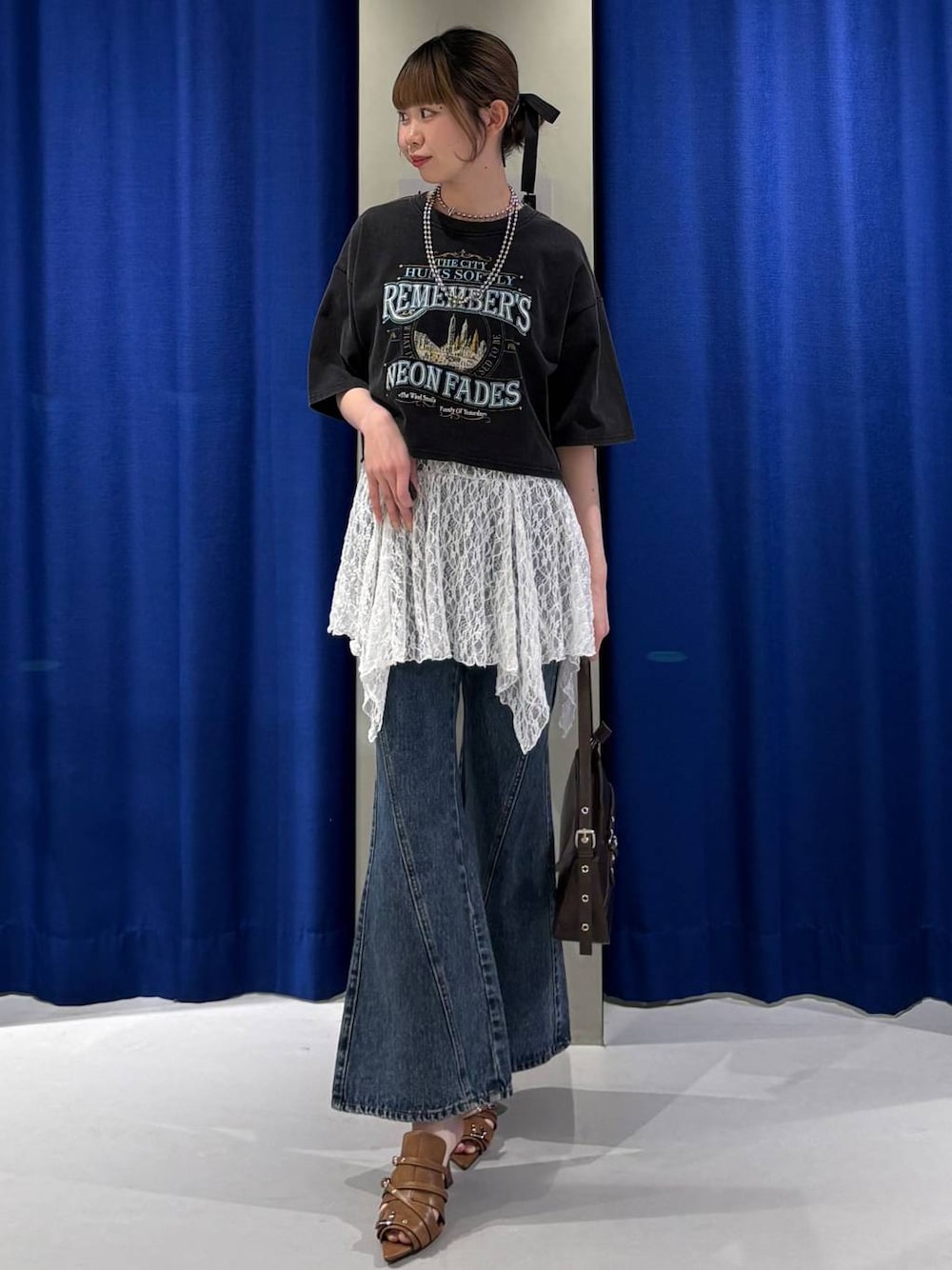 ブルー系のデニムパンツ、ブラウン系のハンドバッグ、グレー系のTシャツ/カットソーを着用したレディースの春コーディネートの1枚目の写真