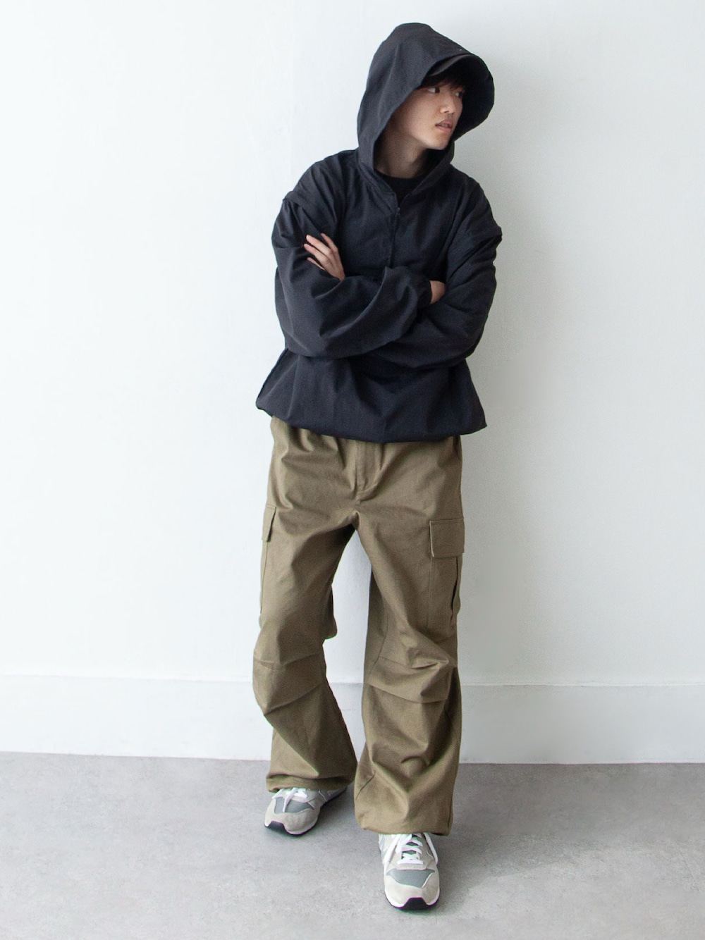 ブラック系のナイロンジャケット、グリーン系のカーゴパンツ、グレー系のスニーカーを着用したメンズの春コーディネートの1枚目の写真