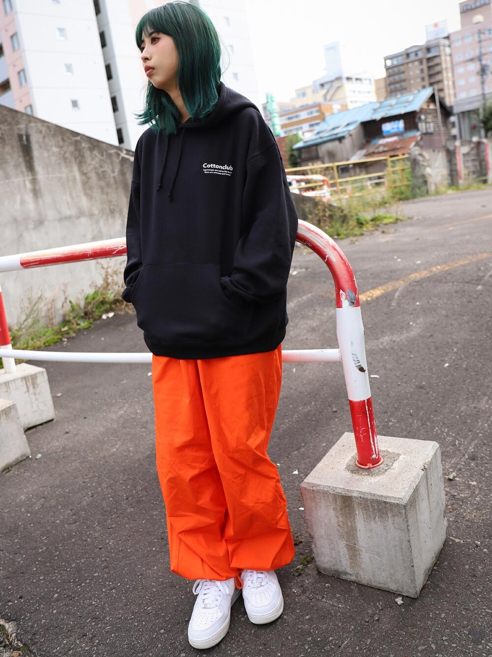 ブラック系のパーカー、オレンジ系のその他パンツ、ホワイト系のスニーカーを着用したレディースの冬コーディネートの1枚目の写真