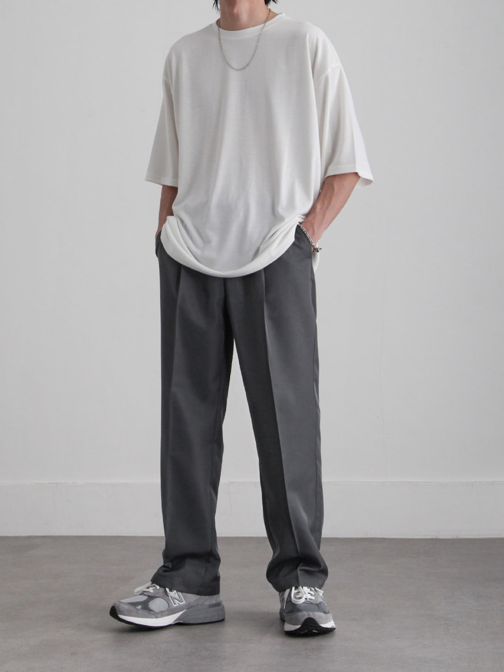 ホワイト系のTシャツ/カットソー、グレー系のスラックス、グレー系のスニーカーを着用したメンズの春コーディネートの1枚目の写真