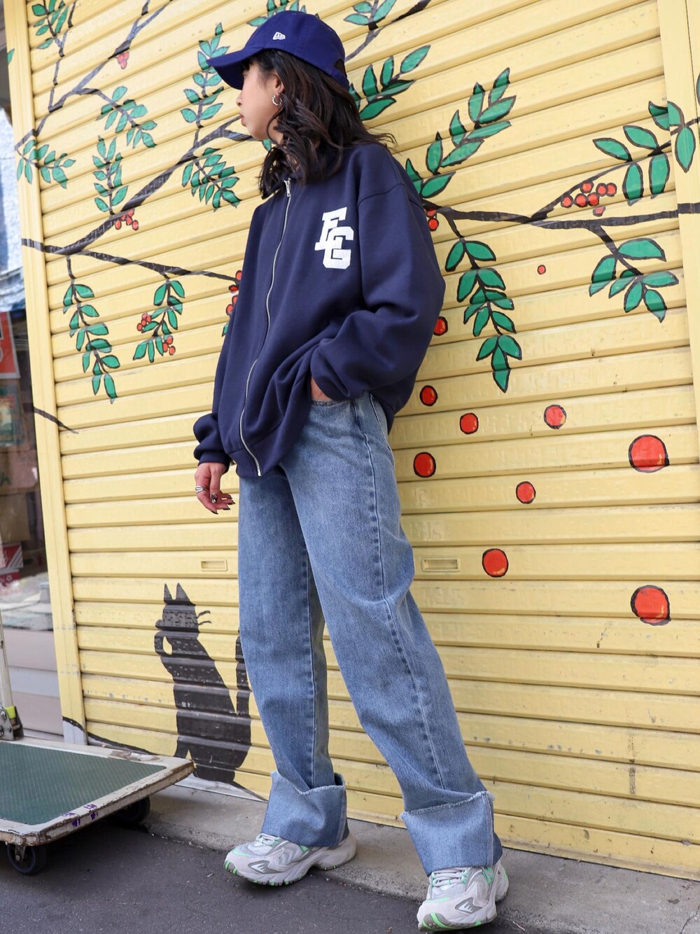 ブルー系のスウェット、グレー系のスニーカー、ブルー系のキャップを着用したレディースの秋コーディネートの1枚目の写真