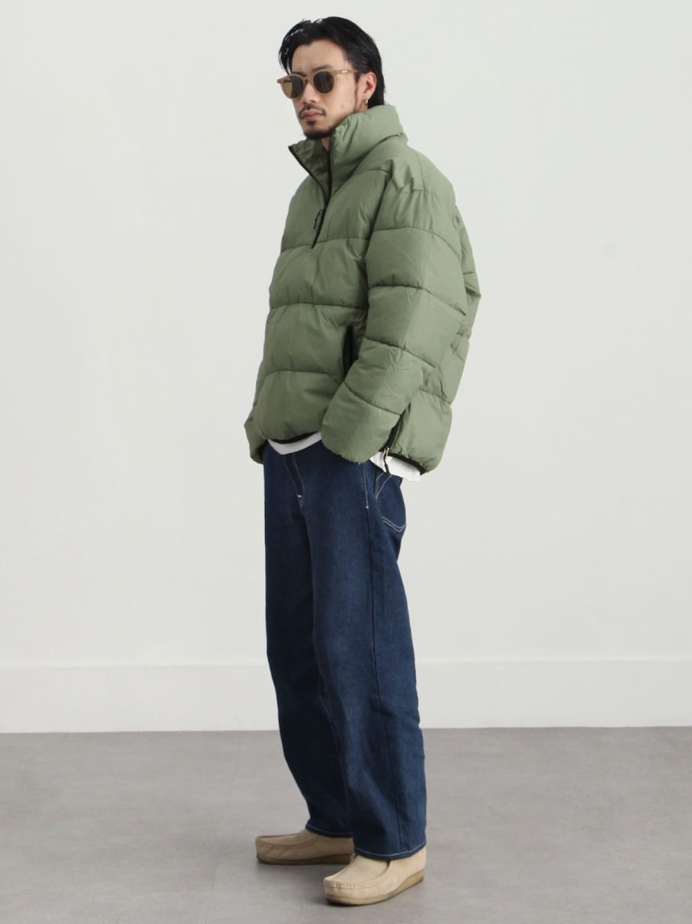 グリーン系のダウンジャケット/コート、ブルー系のデニムパンツ、ベージュ系のモカシン/デッキシューズを着用したメンズの冬コーディネートの1枚目の写真