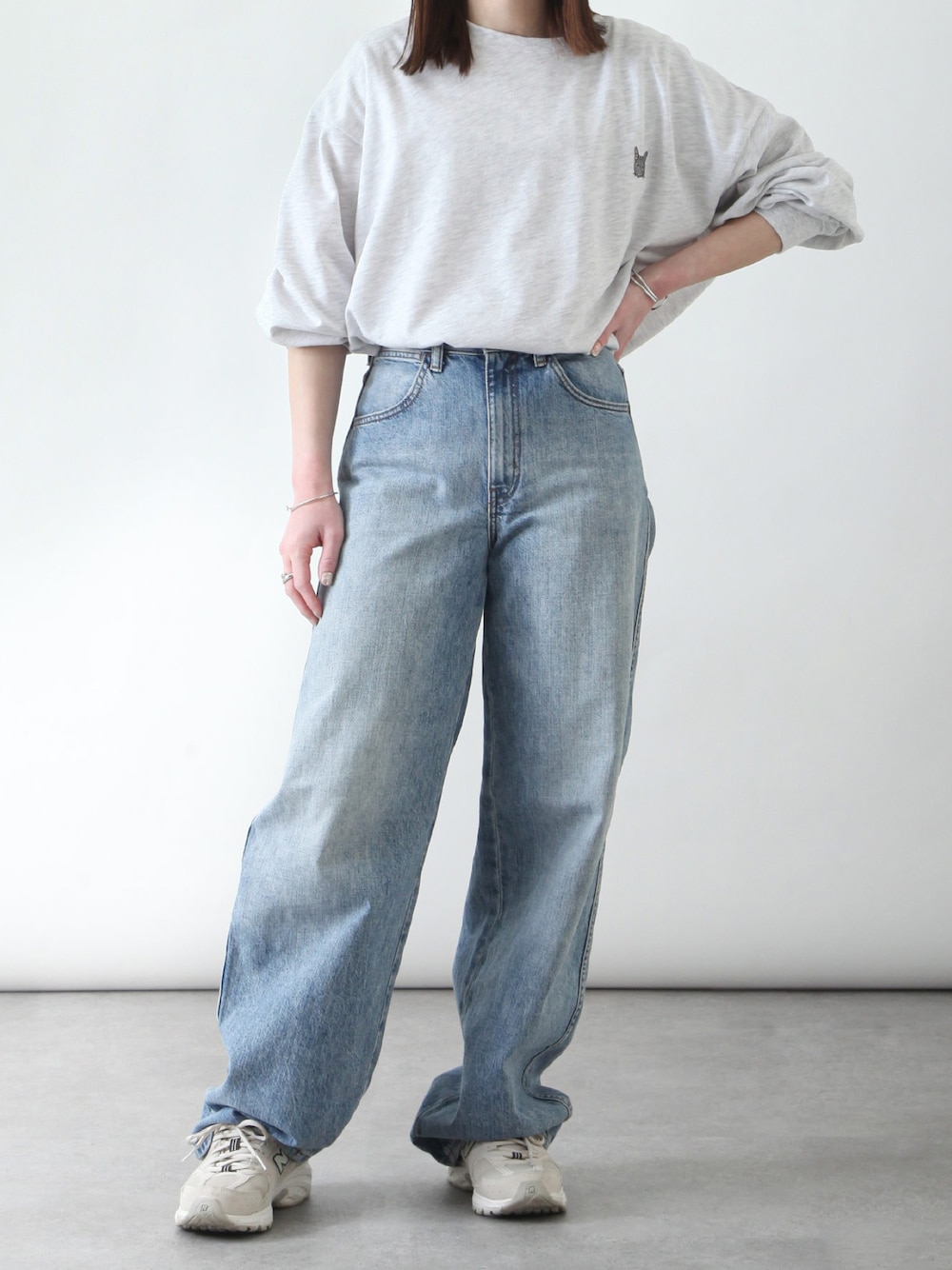 グレー系のTシャツ/カットソー、ベージュ系のスニーカー、ブルー系のデニムパンツを着用したレディースの春コーディネートの1枚目の写真