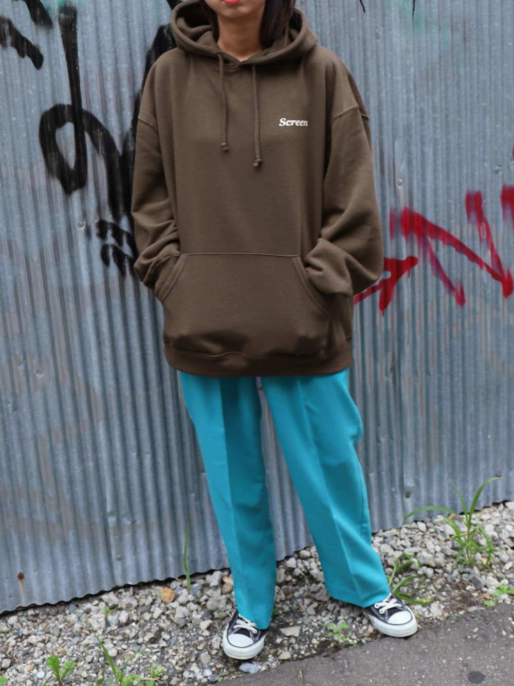 ブルー系のスラックス、ブラウン系のパーカー、ブラック系のスニーカーを着用したレディースの秋コーディネートの1枚目の写真