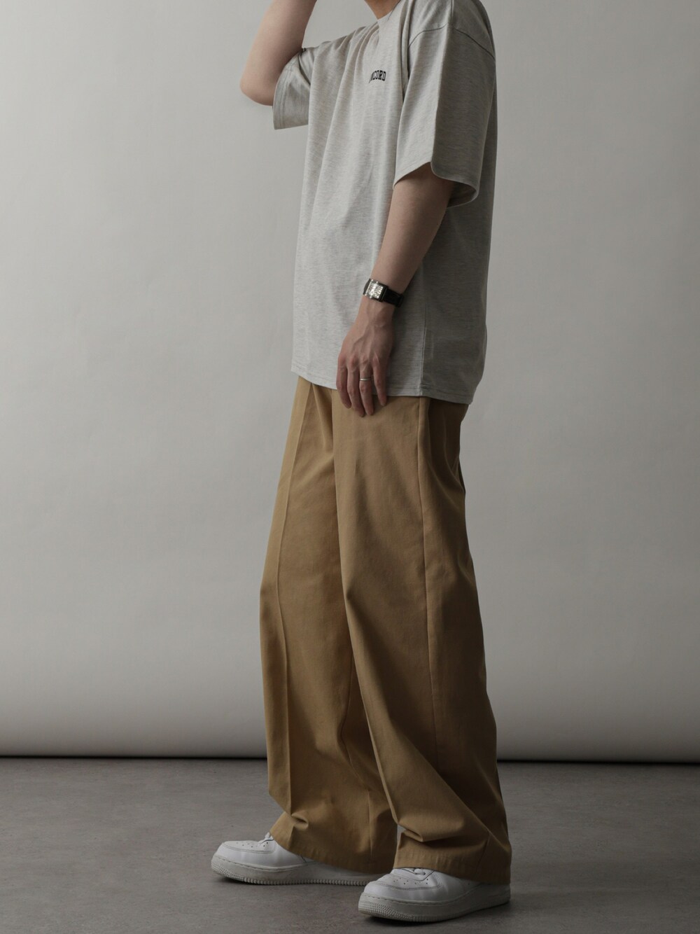 ベージュ系のTシャツ/カットソー、ベージュ系のチノパンツ、ホワイト系のスニーカーを着用したメンズの夏コーディネートの1枚目の写真