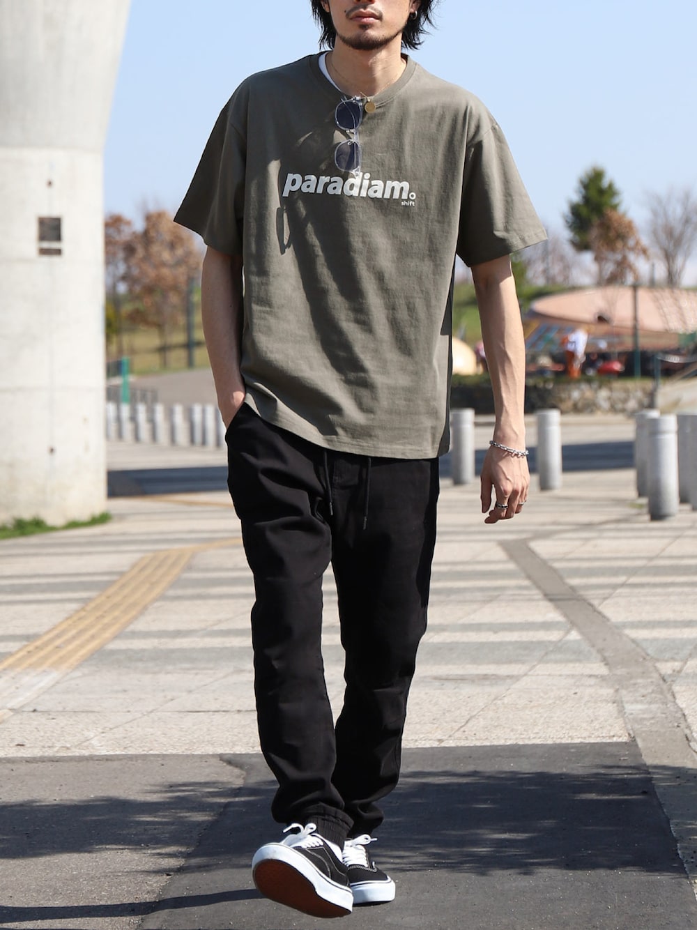 グリーン系のTシャツ/カットソー、ブラック系のチノパンツ、ブラック系のスニーカーを着用したメンズの夏コーディネートの1枚目の写真