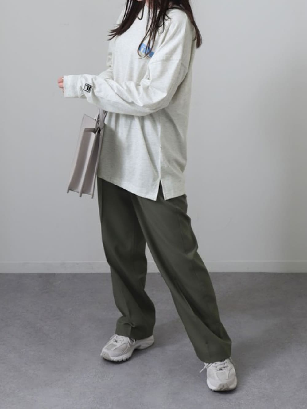 ベージュ系のTシャツ/カットソー、グリーン系のスラックス、ベージュ系のスニーカーを着用したレディースの春コーディネートの1枚目の写真