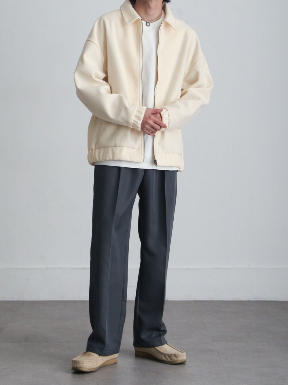 ホワイト系のブルゾン、グレー系のスラックス、ベージュ系のモカシン/デッキシューズを着用したメンズの冬コーディネートの1枚目の写真