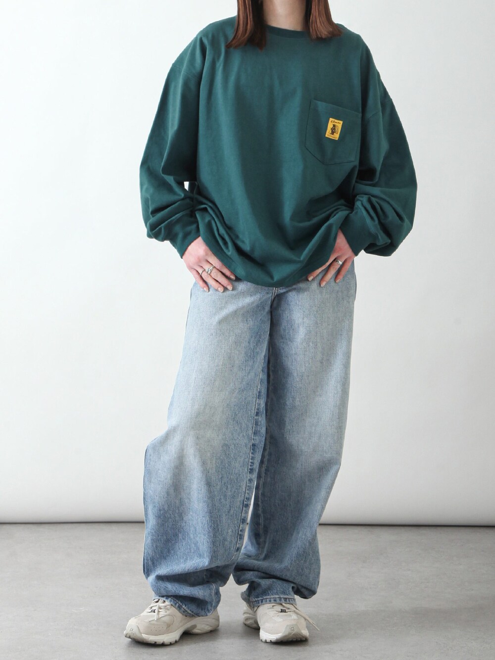 グリーン系のTシャツ/カットソー、ブルー系のデニムパンツ、ベージュ系のスニーカーを着用したレディースの春コーディネートの1枚目の写真