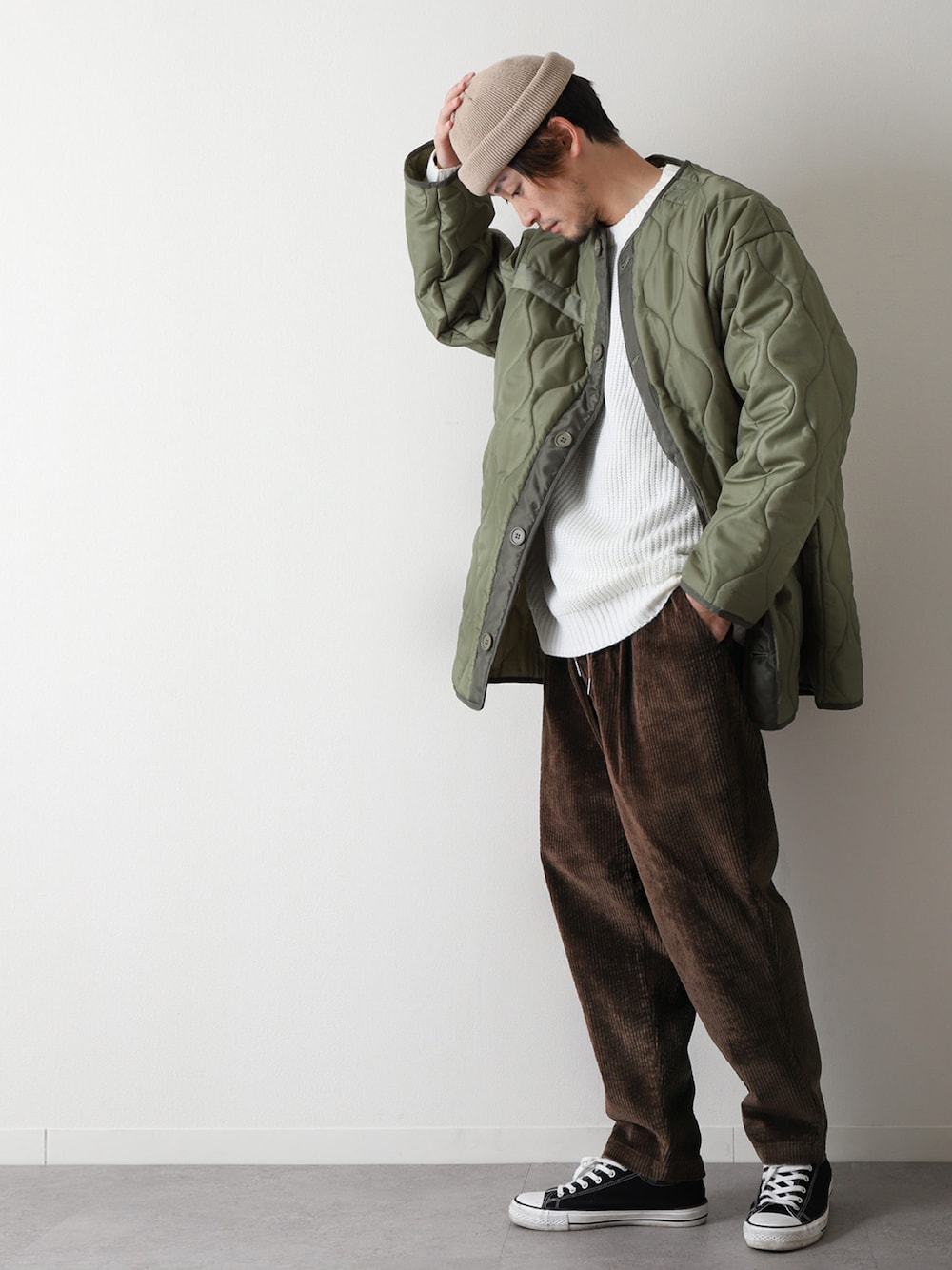 グリーン系のダウンジャケット/コート、ホワイト系のニット/セーター、ブラック系のスニーカーを着用したメンズの冬コーディネートの1枚目の写真
