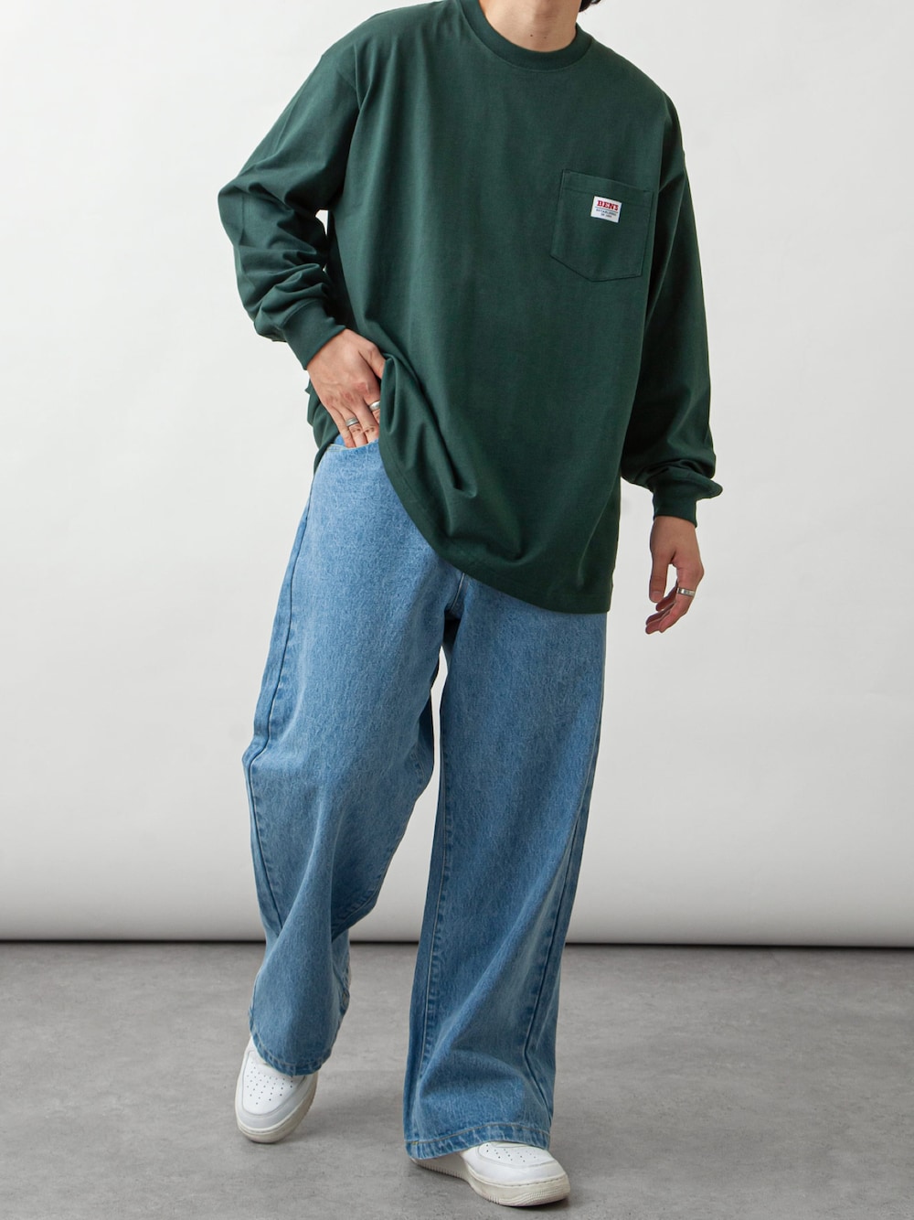 グリーン系のTシャツ/カットソー、ブルー系のデニムパンツ、ホワイト系のスニーカーを着用したメンズの秋コーディネートの1枚目の写真