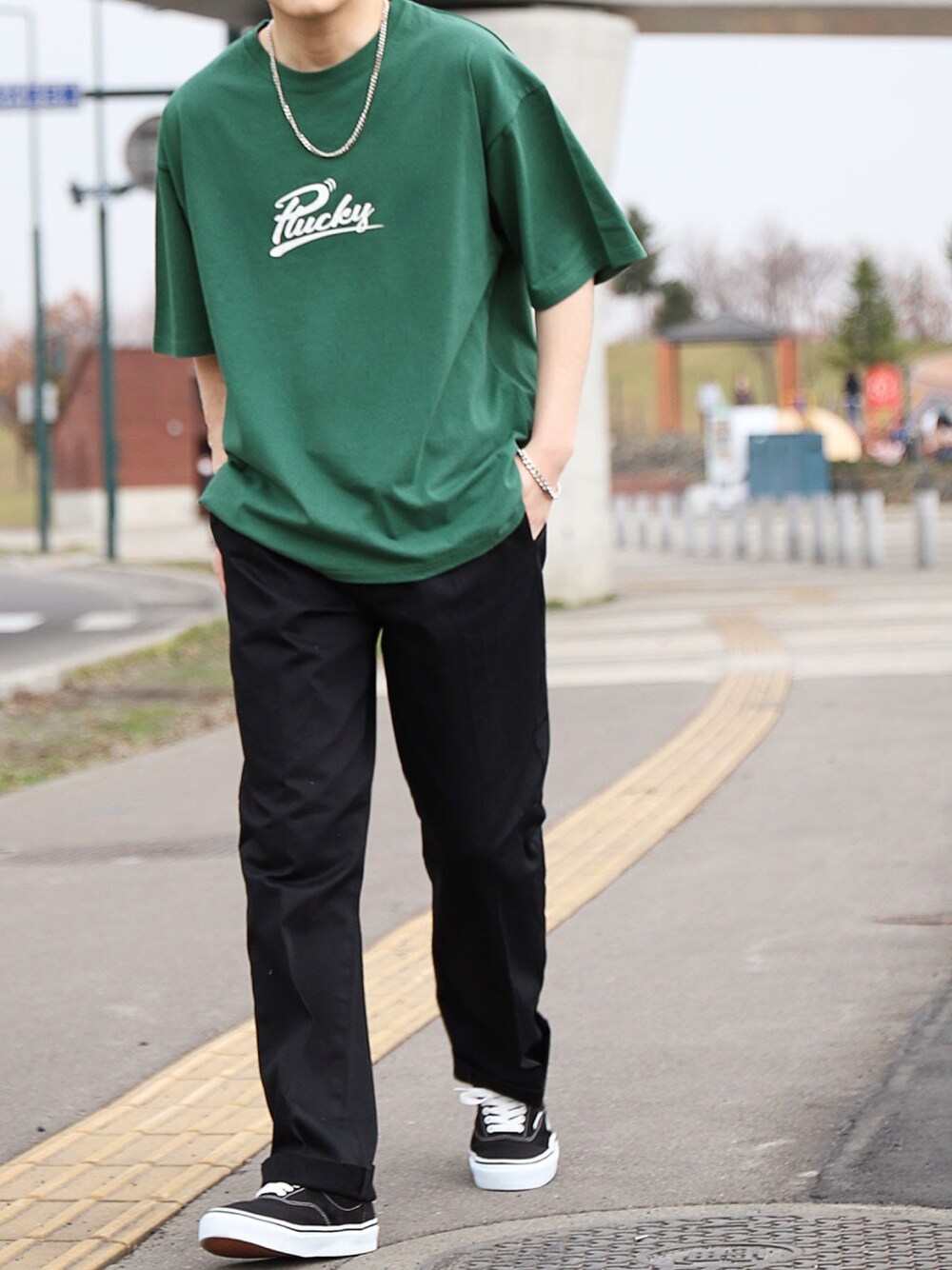 グリーン系のTシャツ/カットソー、ブラック系のチノパンツ、ブラック系のスニーカーを着用したメンズの春コーディネートの1枚目の写真