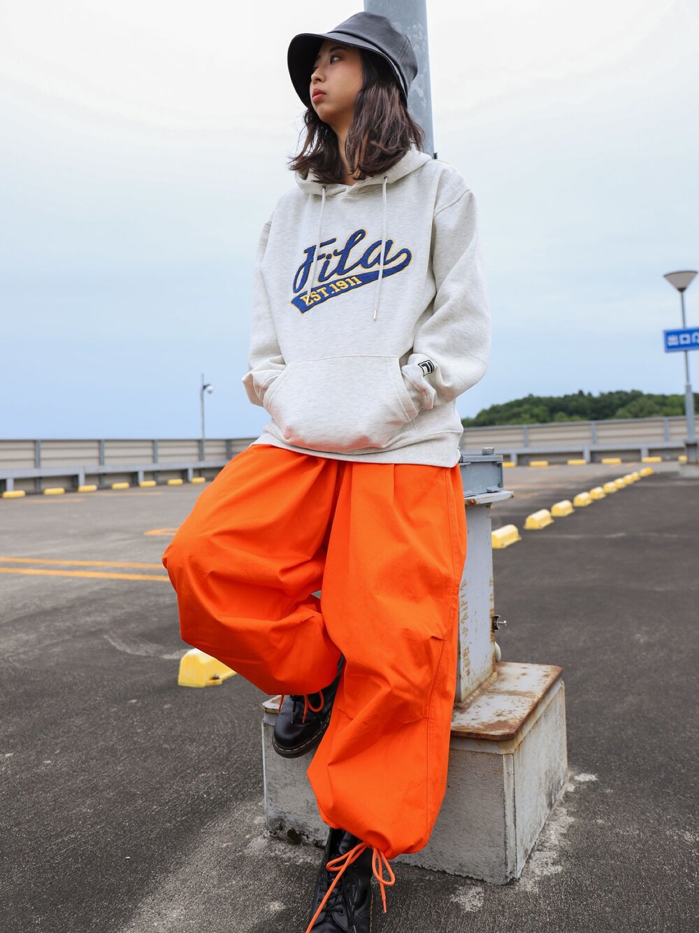 ベージュ系のパーカー、オレンジ系のその他パンツ、ブラック系のブーツを着用したレディースの秋コーディネートの1枚目の写真