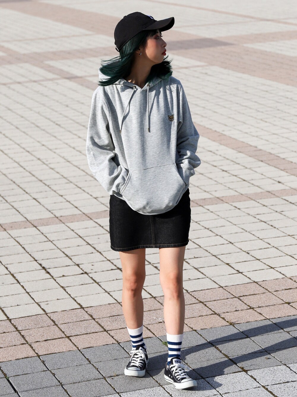 グレー系のパーカー、ブルー系のデニムスカート、ブラック系のスニーカーを着用したレディースの秋コーディネートの1枚目の写真