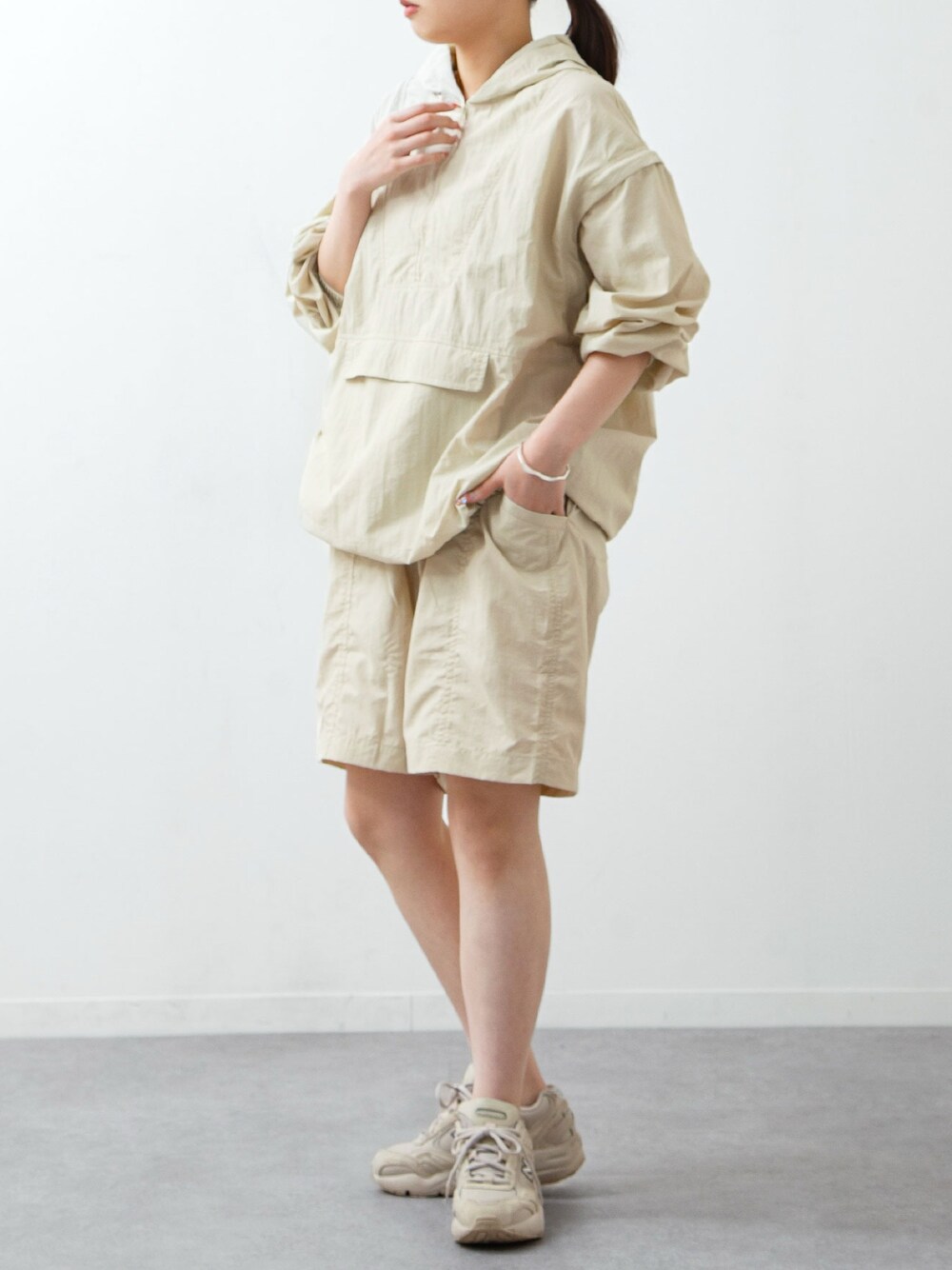 ホワイト系のナイロンジャケット、ホワイト系のその他パンツ、ベージュ系のスニーカーを着用したレディースの春コーディネートの1枚目の写真